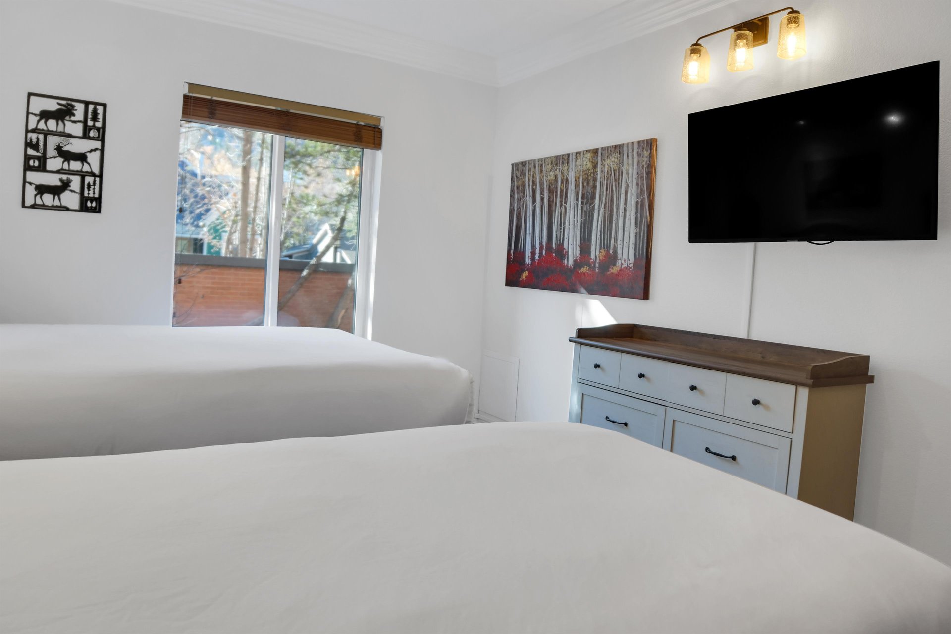 The second bedroom has two twin beds, dresser, and wall mounted TV above the dresser.