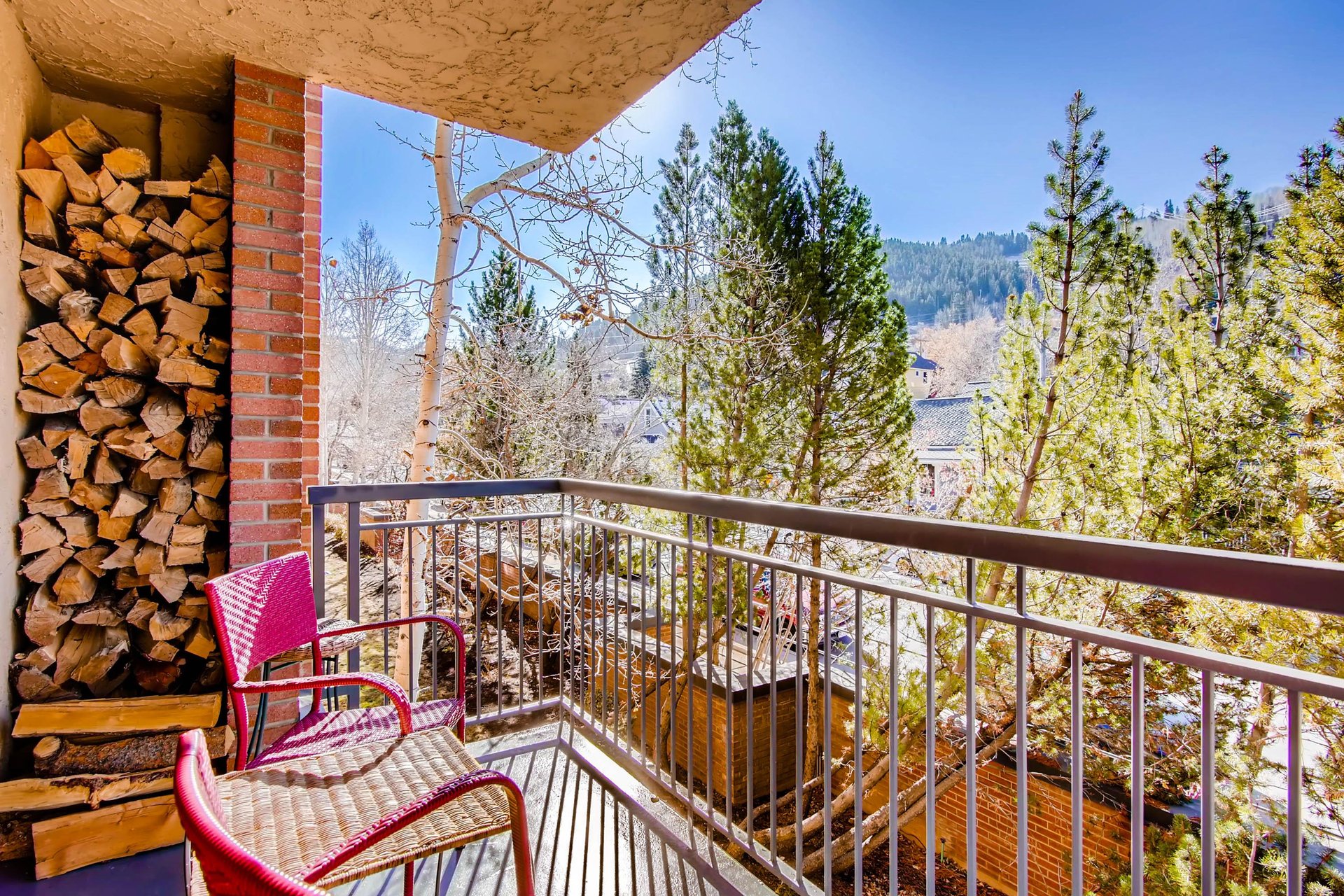 Park Station 121s private balcony with two sitting chairs and trees and mountains beyond.