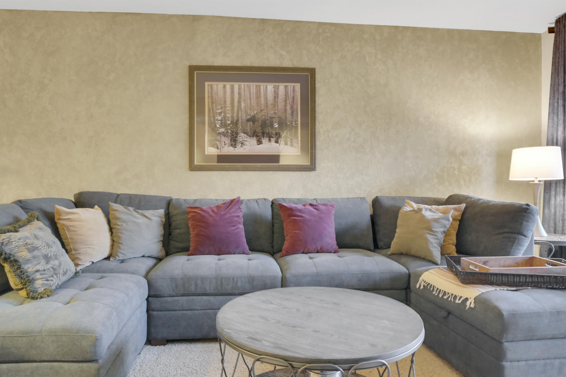 Park Station 122s living room has a grey upholstered sofa, throw pillows, modern round coffee table, and picture on the wall.