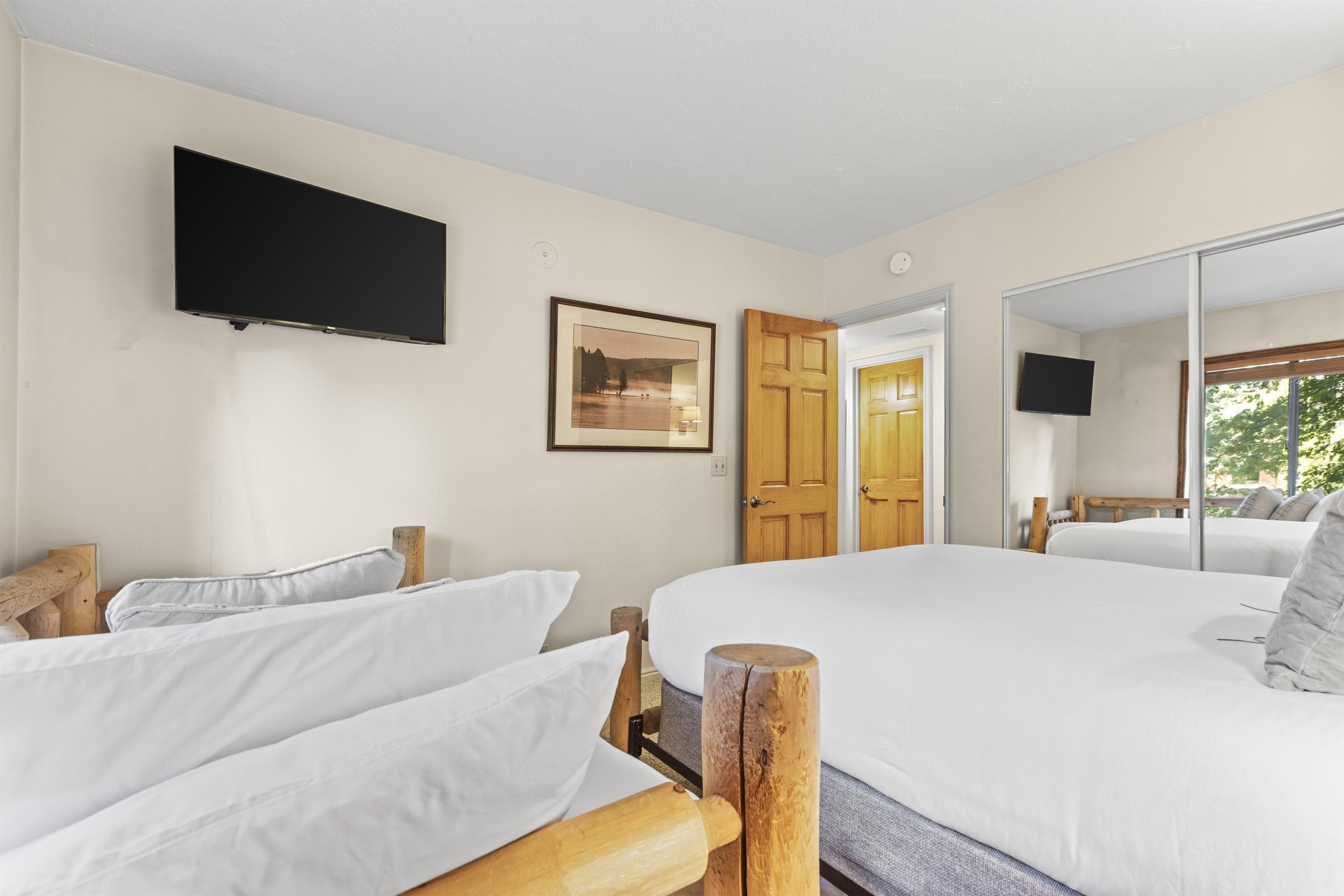 The second bedroom with a queen bed, twin bed and wall mounted TV.