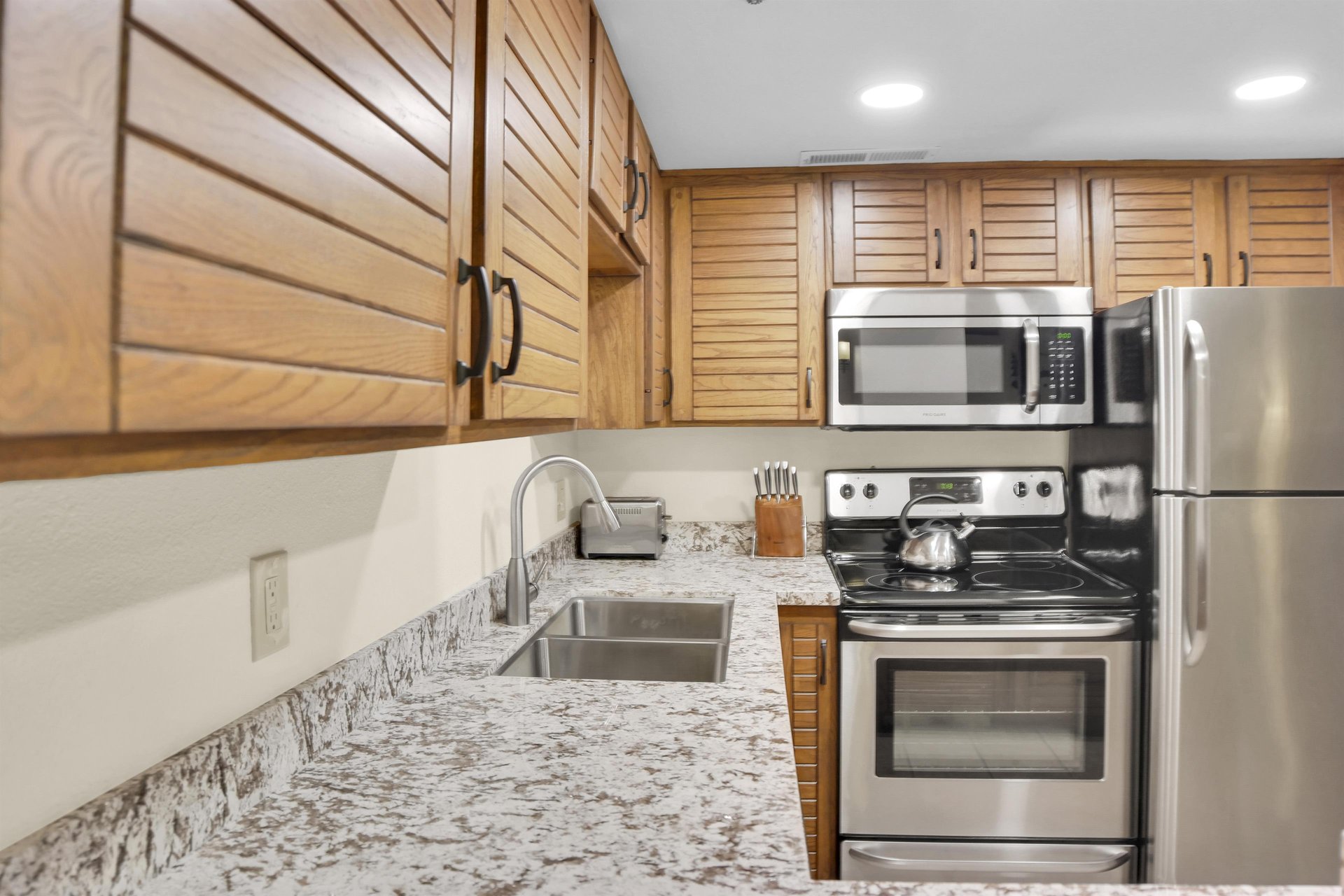 Park Station 214s kitchen offers stainless steel appliances, wood cabinets, and grey and white counter tops.