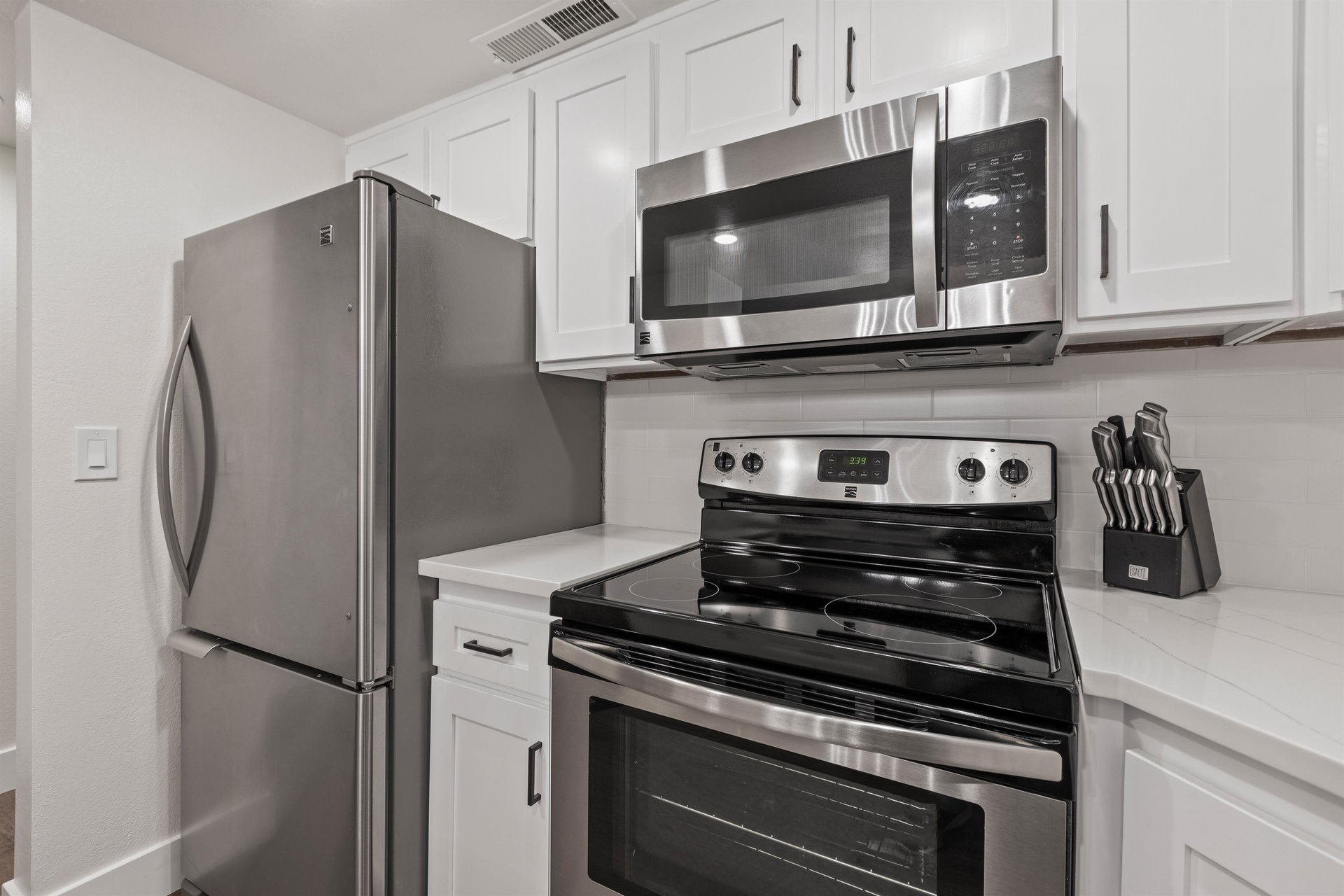 The kitchen has stainless steel appliances and white cabinets.