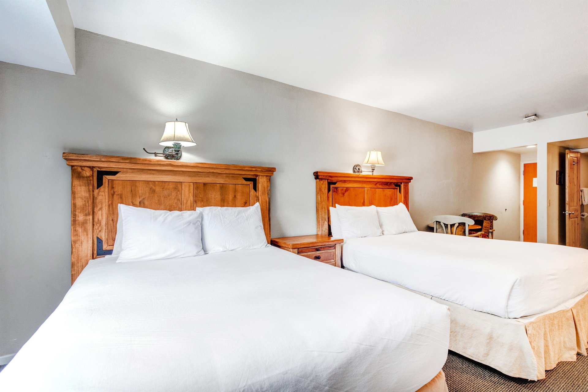 One of the bedrooms offer two queen beds with wooden furniture.