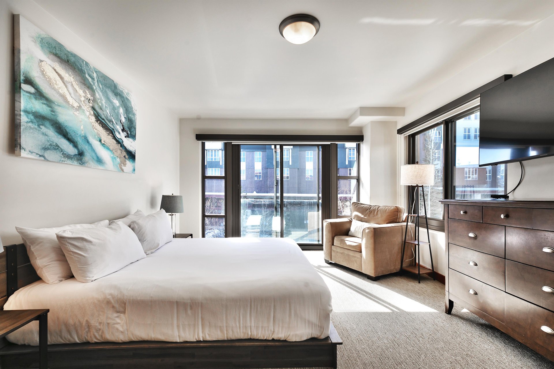 Luxurious king platform bed in the main bedroom and cozy overstuffed chair