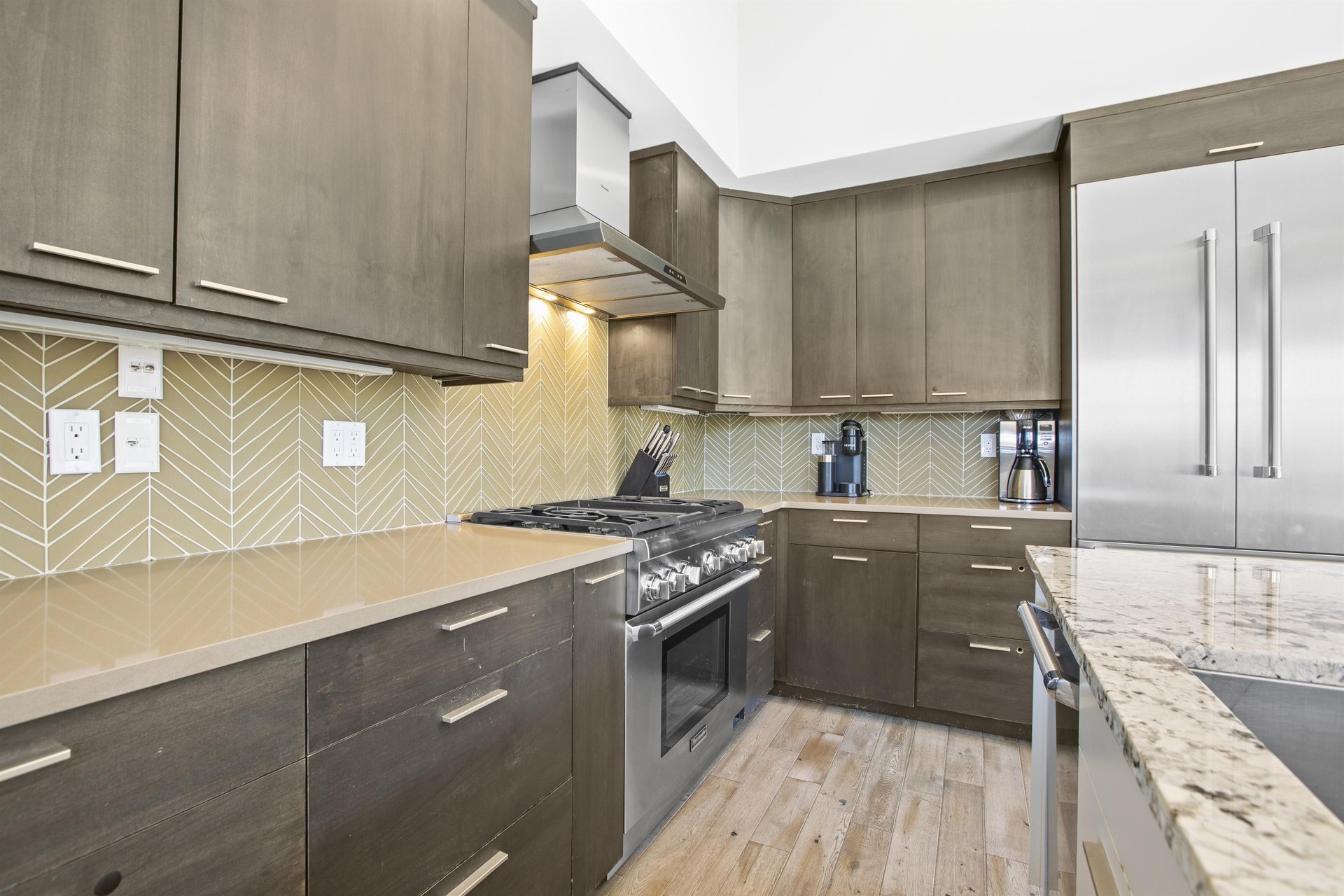 Open concept kitchen with waterfall island and stainless steel appliances.
