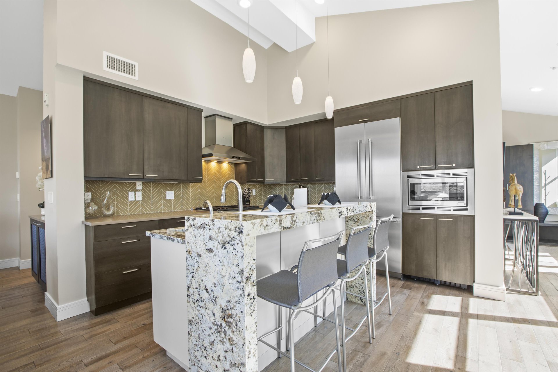 Open concept kitchen with waterfall island and stainless steel appliances.