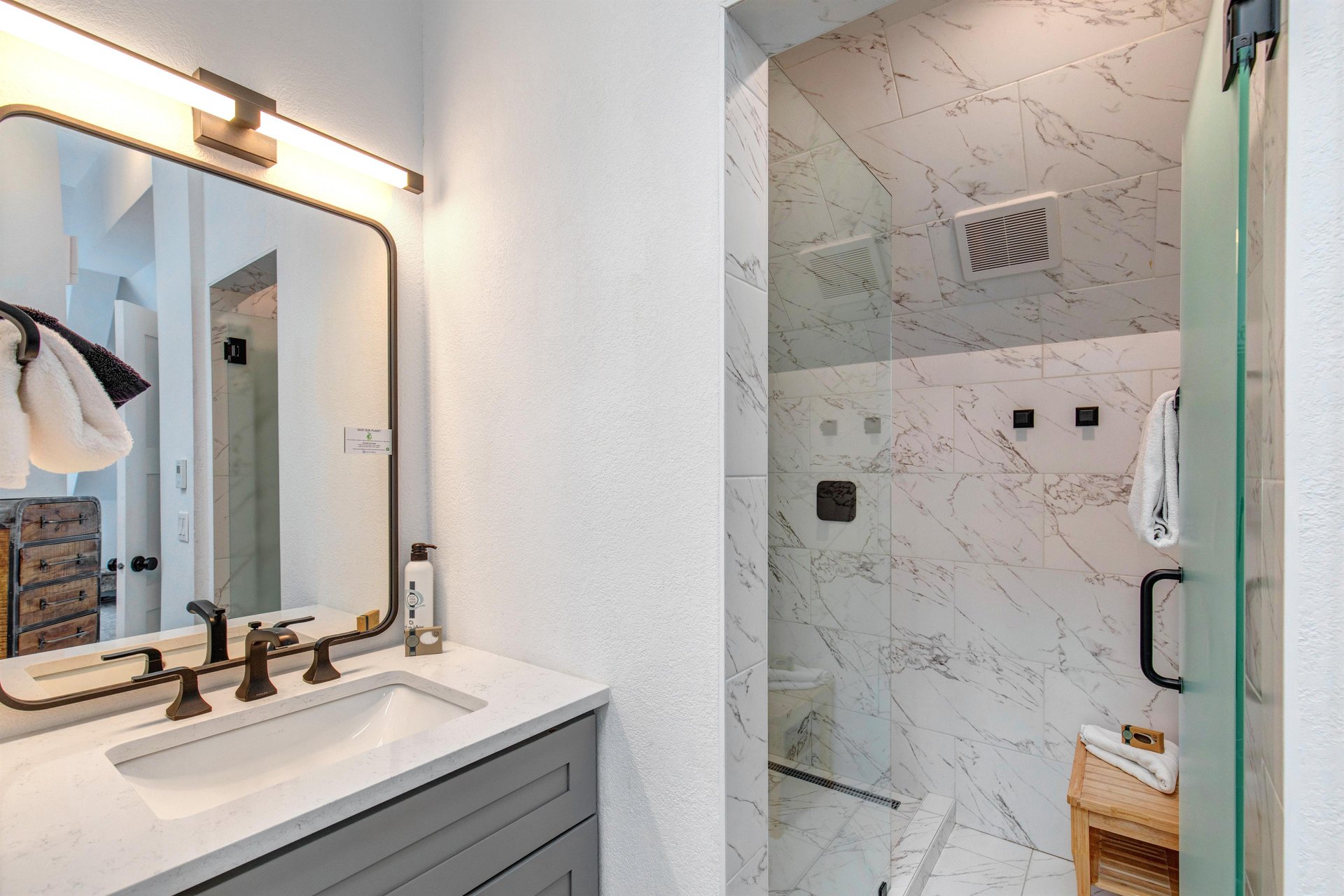 The attached bathroom with single sink vanity and walk in shower.