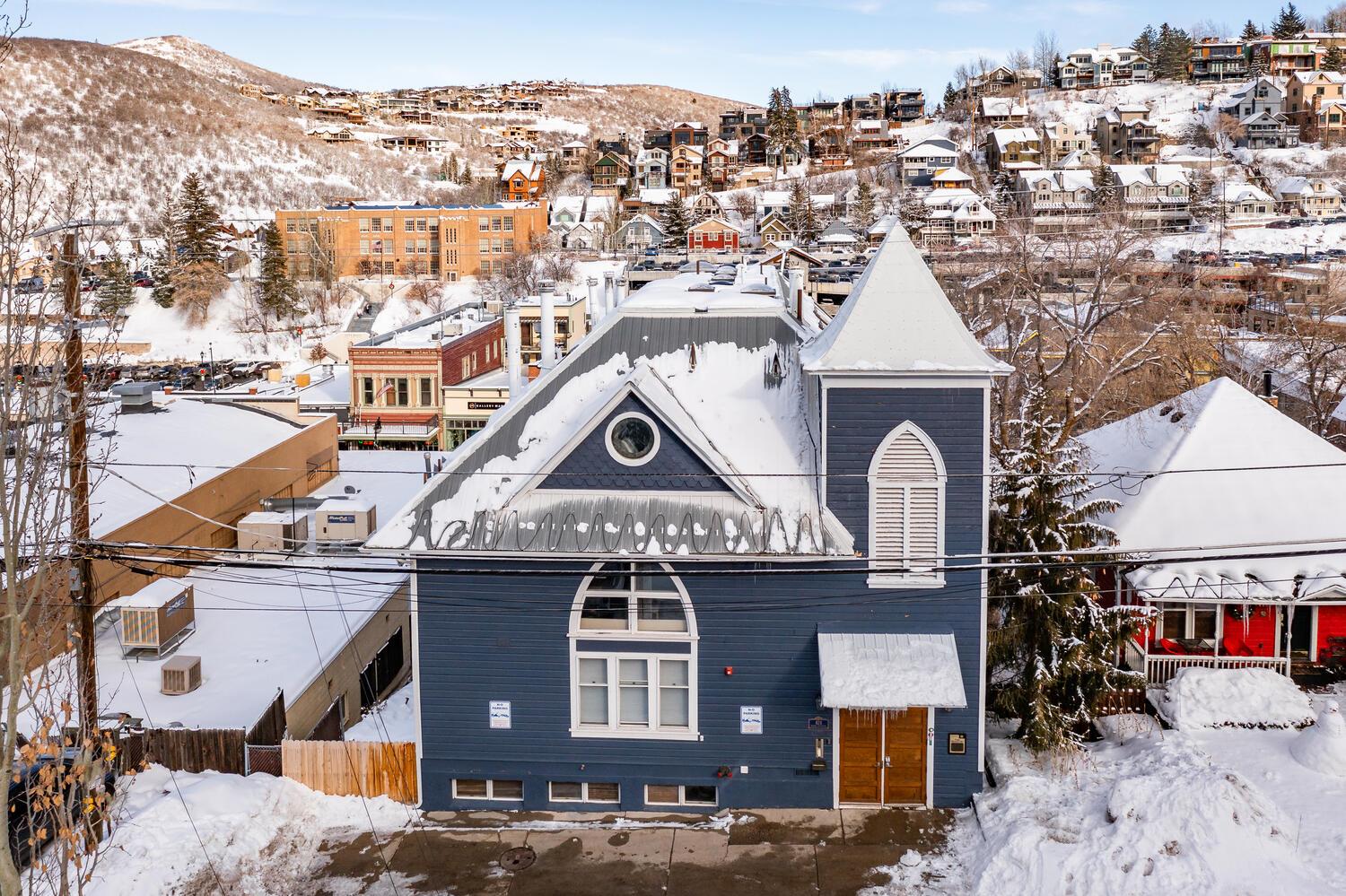 Blue Church Lodge exterior with the snowy Historic Main Street in Park City and Park City Mountain behind.