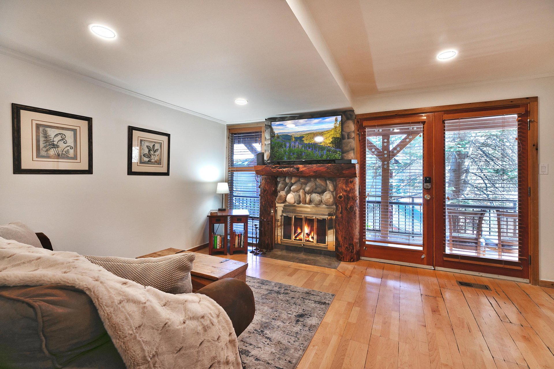 Open living area with hardwood floors, gas fireplace and mantle mounted TV