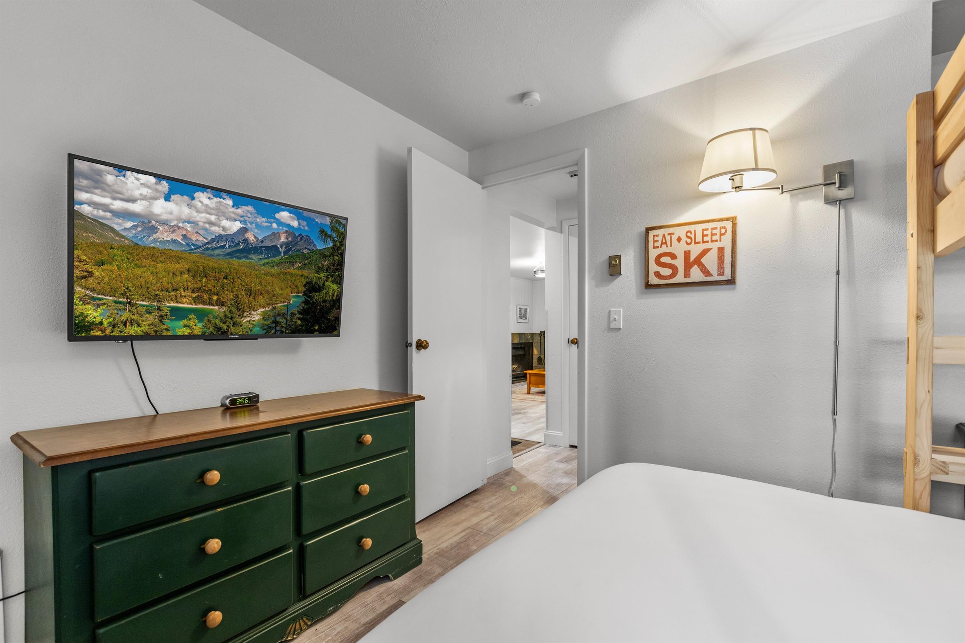 The second bedroom offers a green dresser and flat screen TV.