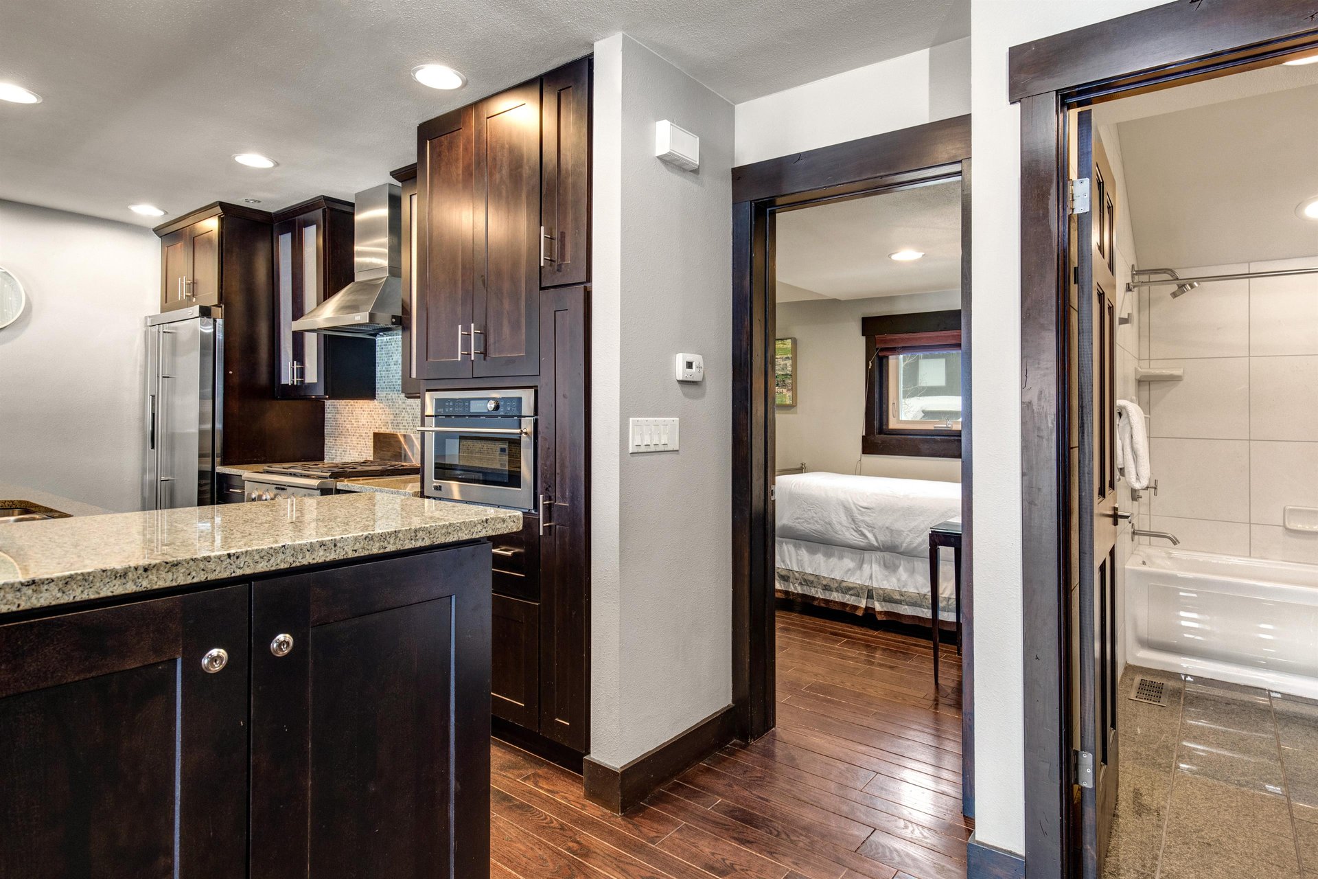 The wellequipped kitchen has dark wood cabinets, stainless steel appliances and bedroom off the kitchen.