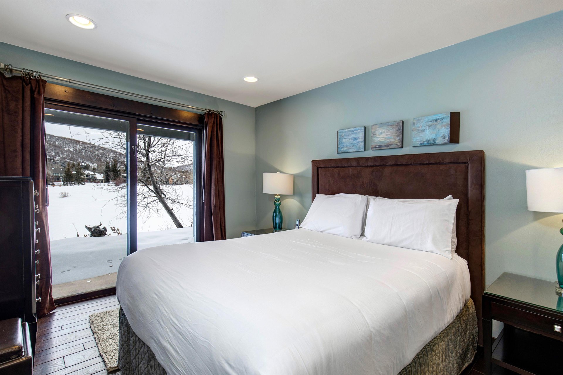 Another bedroom with a queen size bed and sliding glass doors with mountain and lake views.