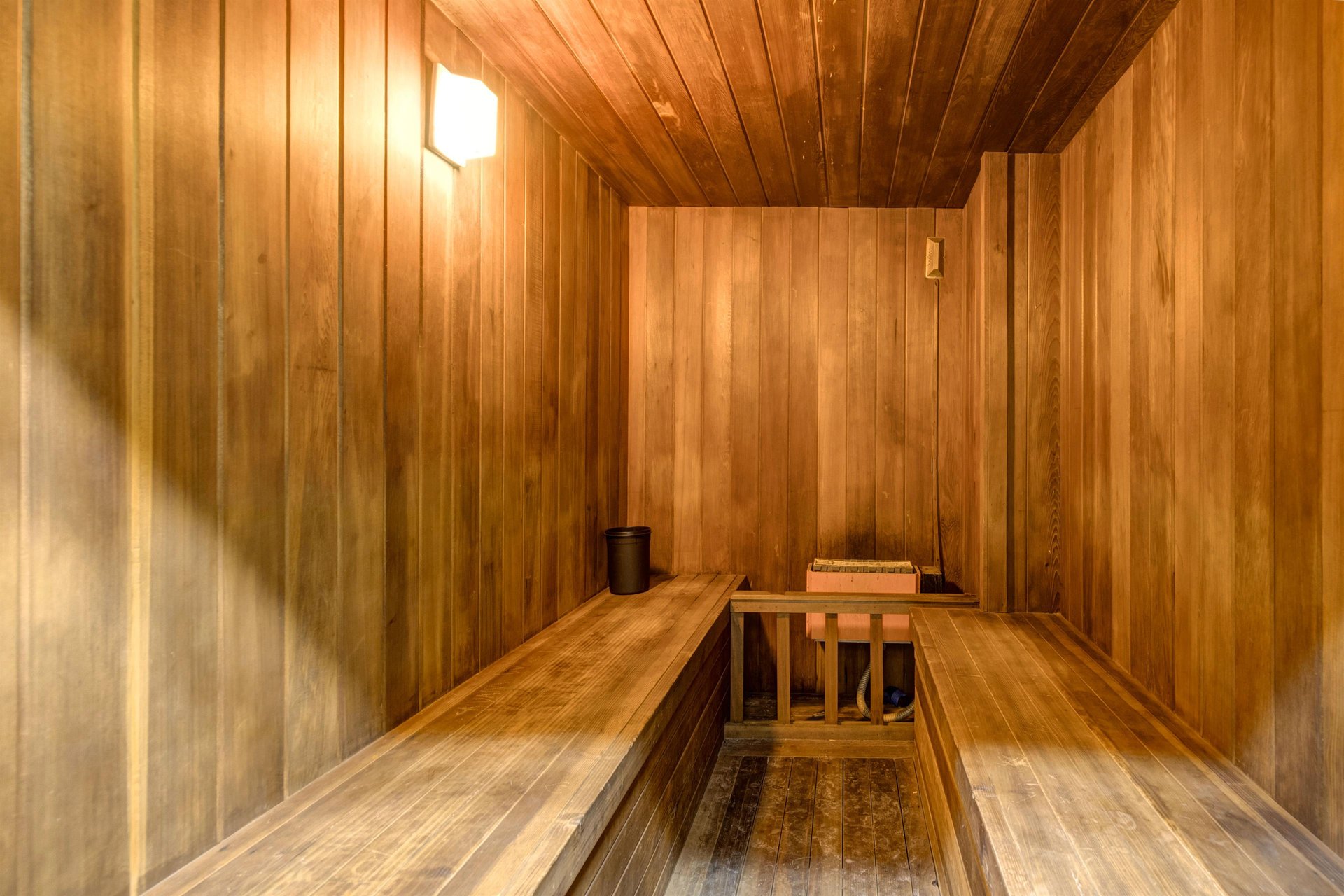 Step into your private wooden sauna with warm cedar walls and soft lighting.