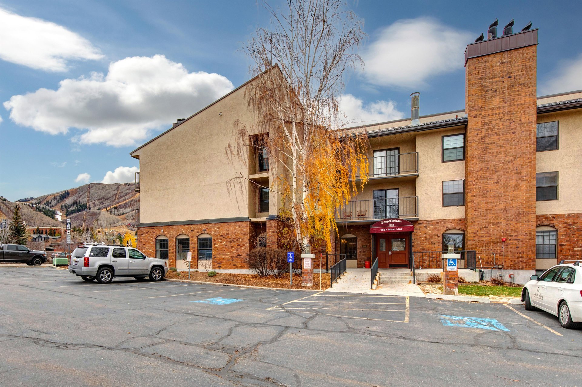 Property exterior featuring brick and stucco construction with mountain backdrop and convenient parking access.
