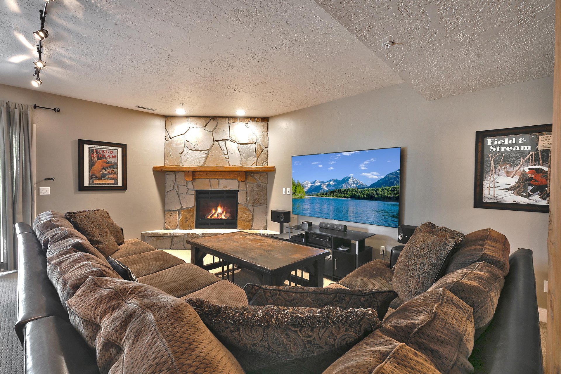 Den lounge with large sectional, 83 flat screen TV and flagstone fireplace wall