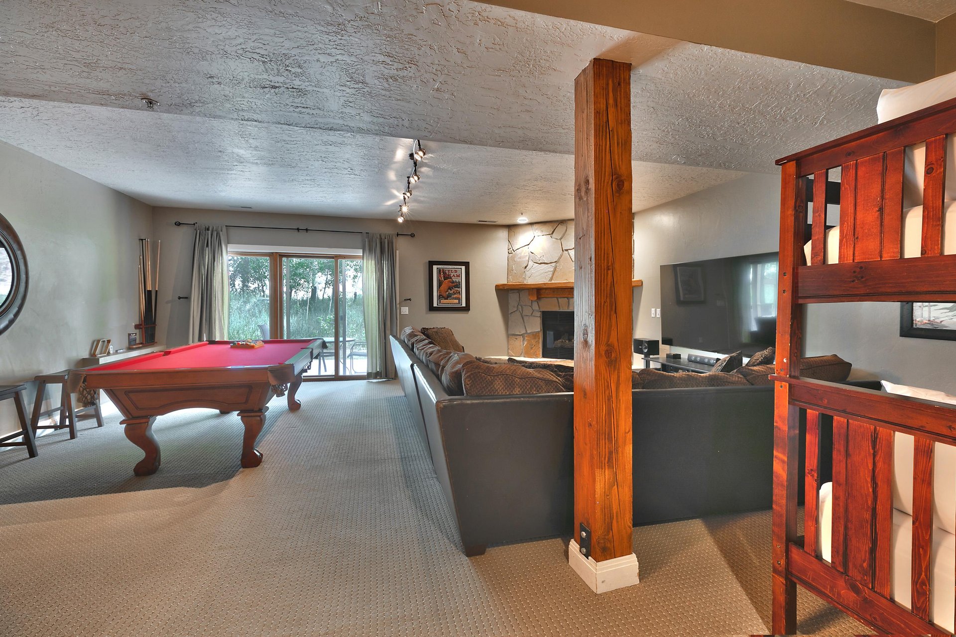 Spacious den features cozy movie space, bunks, a pool table and access to the backyard