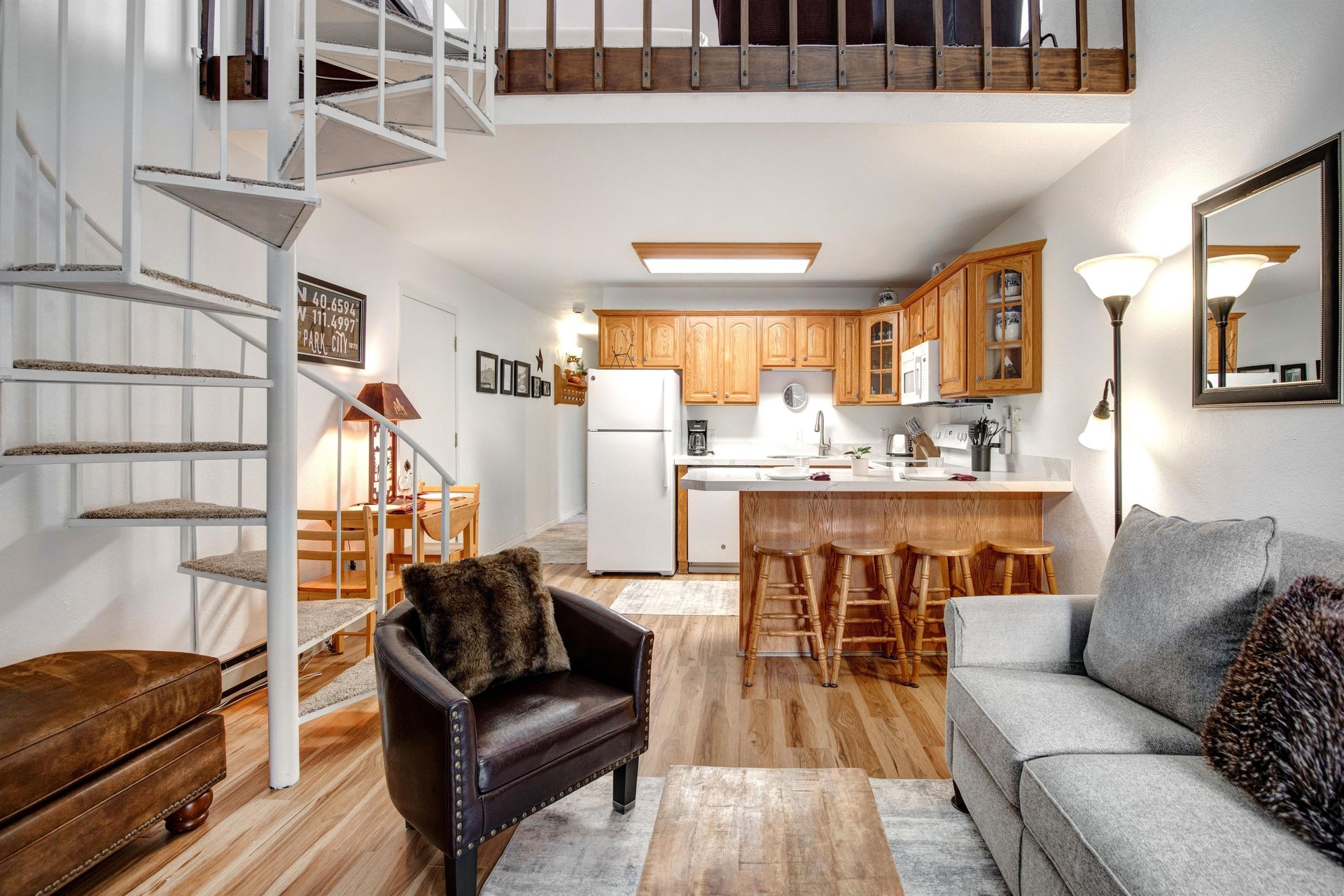 Relax in your spacious openconcept living area featuring a fully equipped kitchen, comfortable seating, and charming spiral staircase to the loft above.