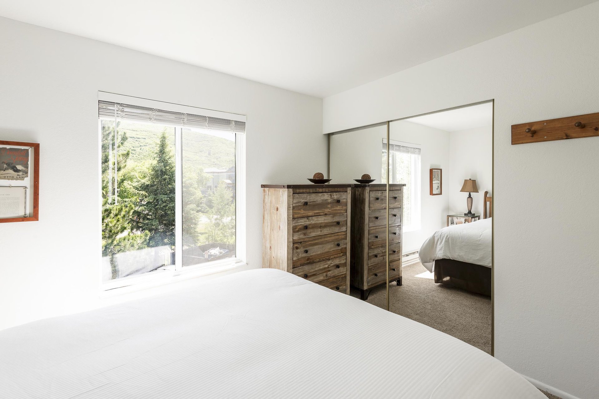 Main bedroom with mirrored bypass closet doors and coat rack