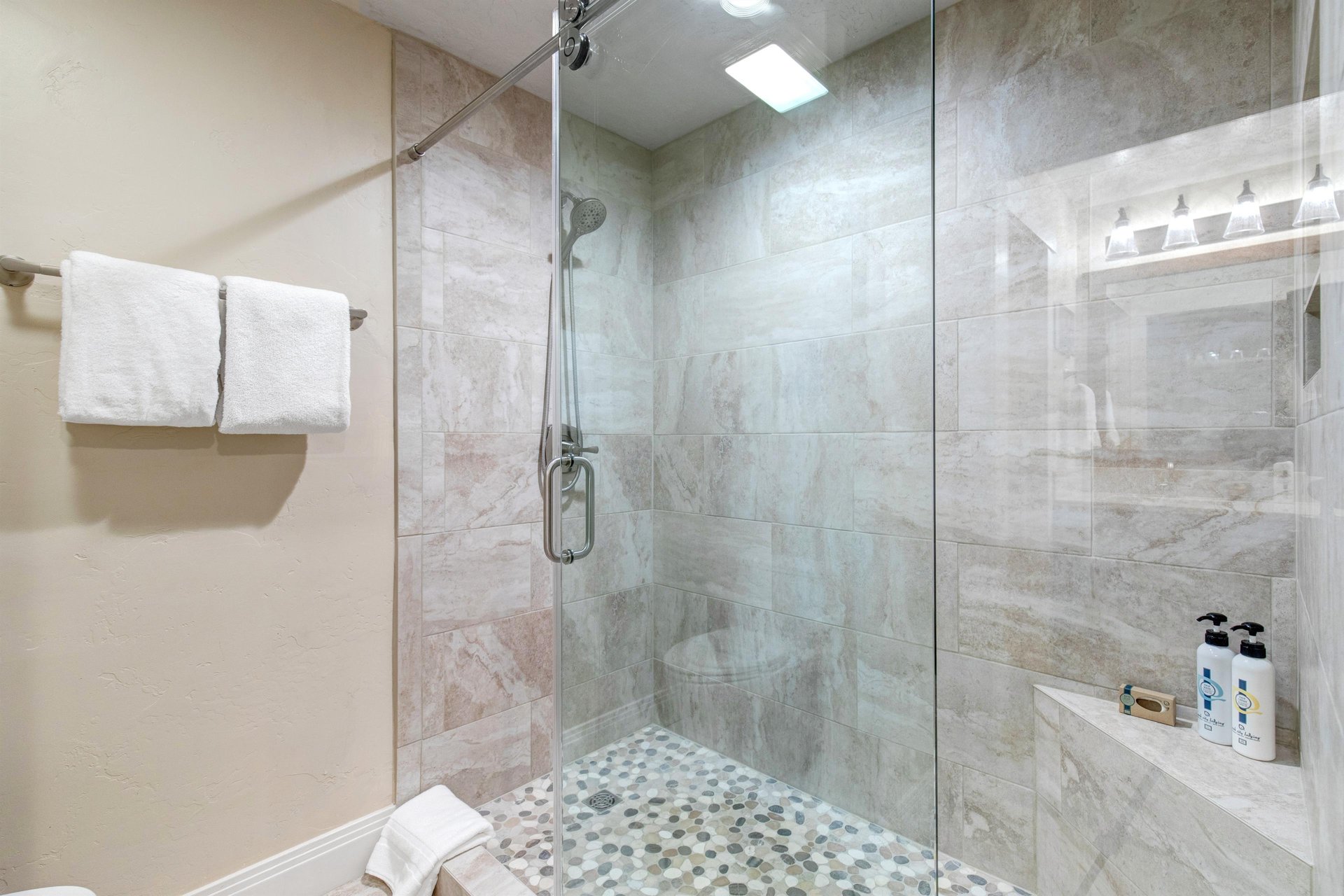 Step into your private spalike shower, where soft rainfall and smooth pebble flooring invite you to unwind. Fresh towels and premium amenities are ready for your refreshing escape.