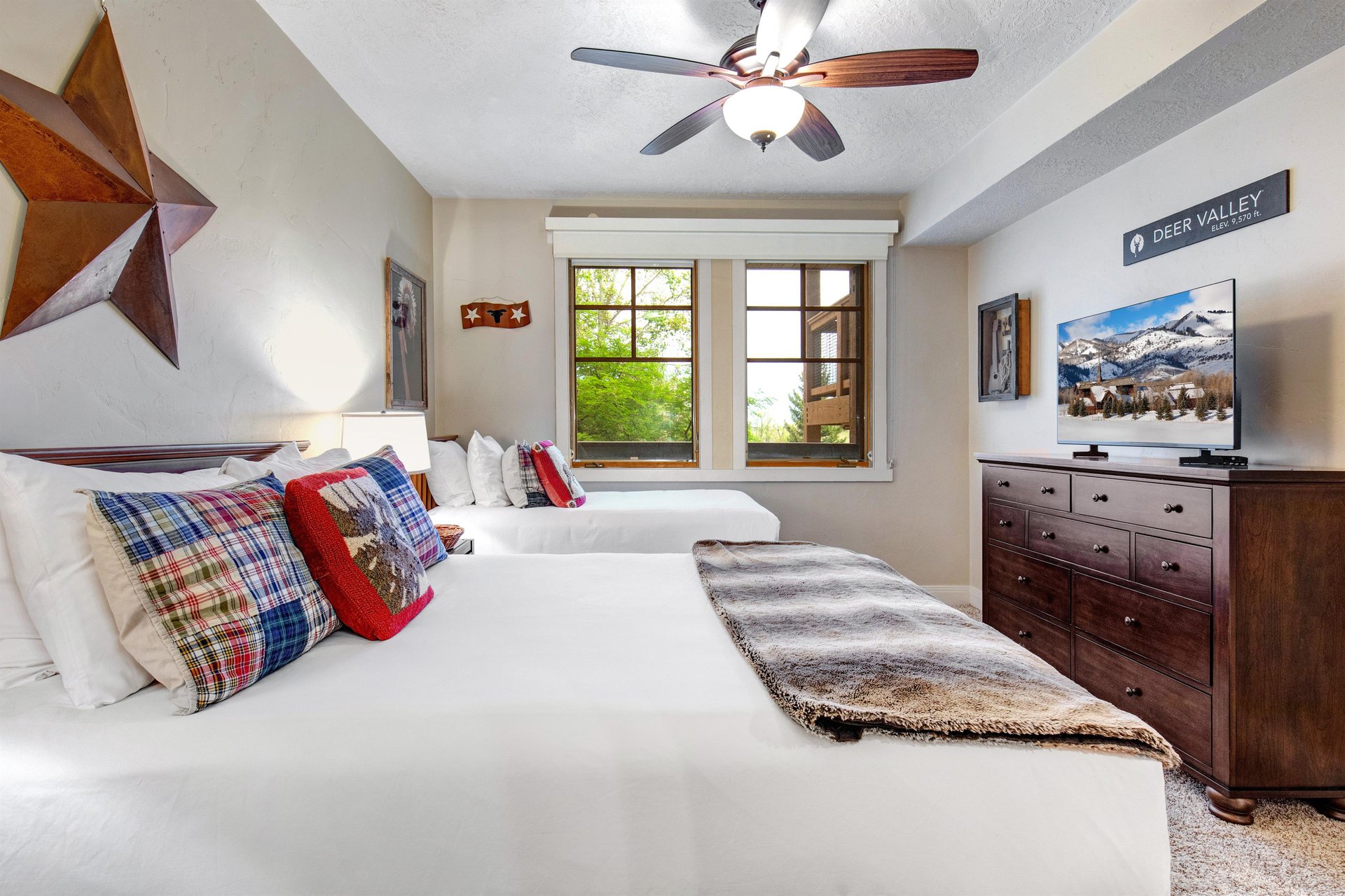Sink into crisp white linens and rustic mountain charm in your cozy bedroom, where a ceiling fan keeps you comfortable and local décor invites restful sleep after your adventures.