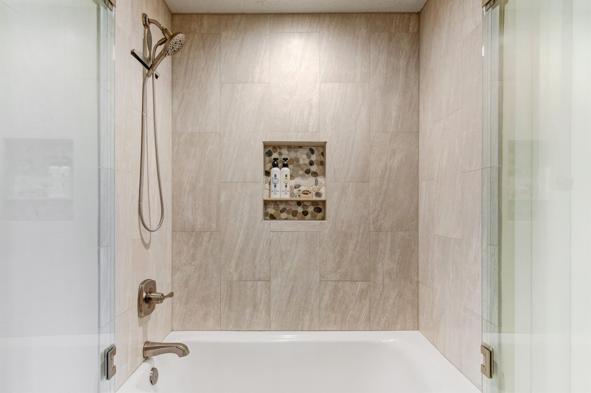 Your private bathroom features a sleek tubshower combo with a modern handheld showerhead. Elegant tile walls and a builtin niche provide both style and convenience for your stay.
