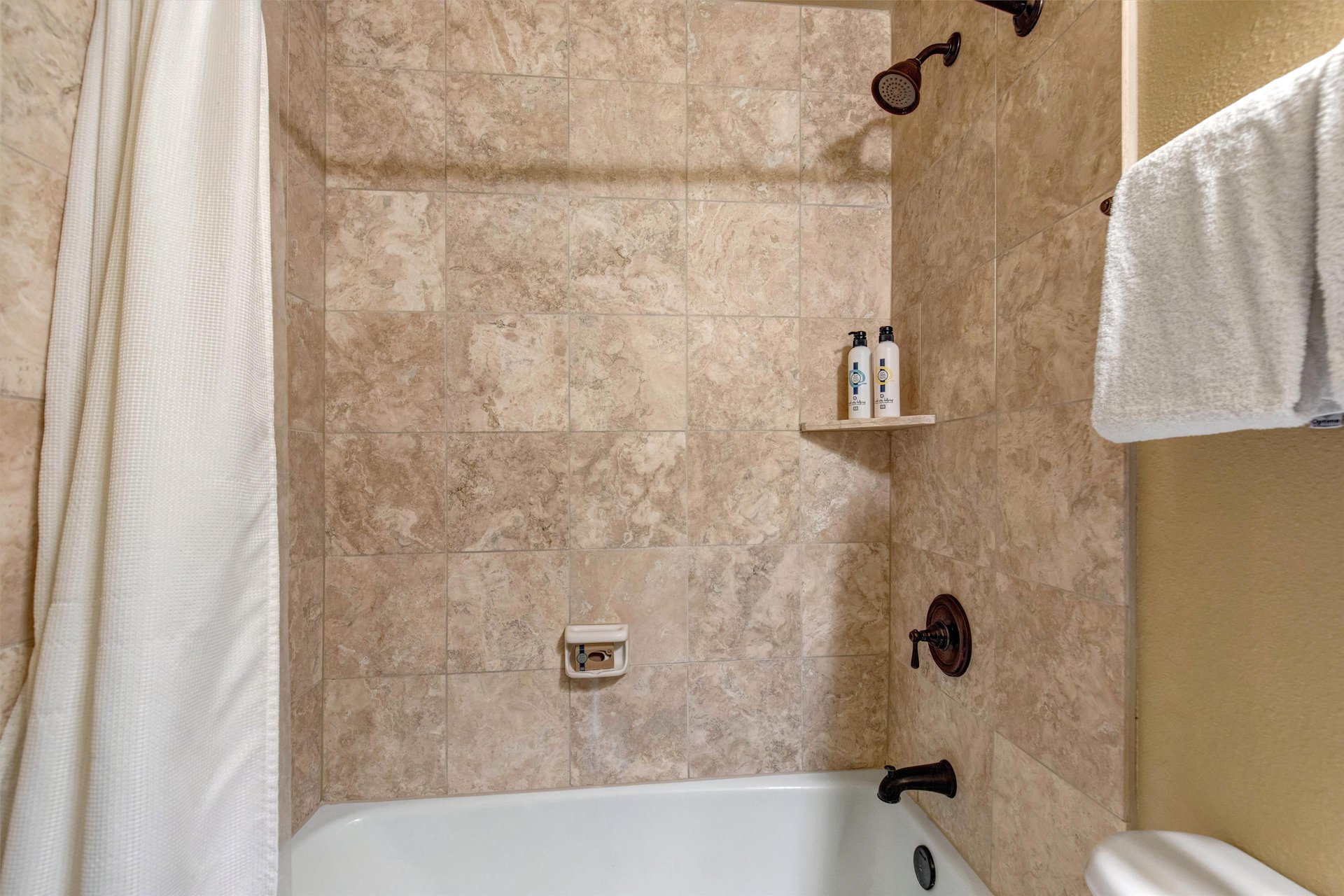 Unwind in your elegant bathroom featuring beautiful travertine tiles, premium amenities, and plush towels.