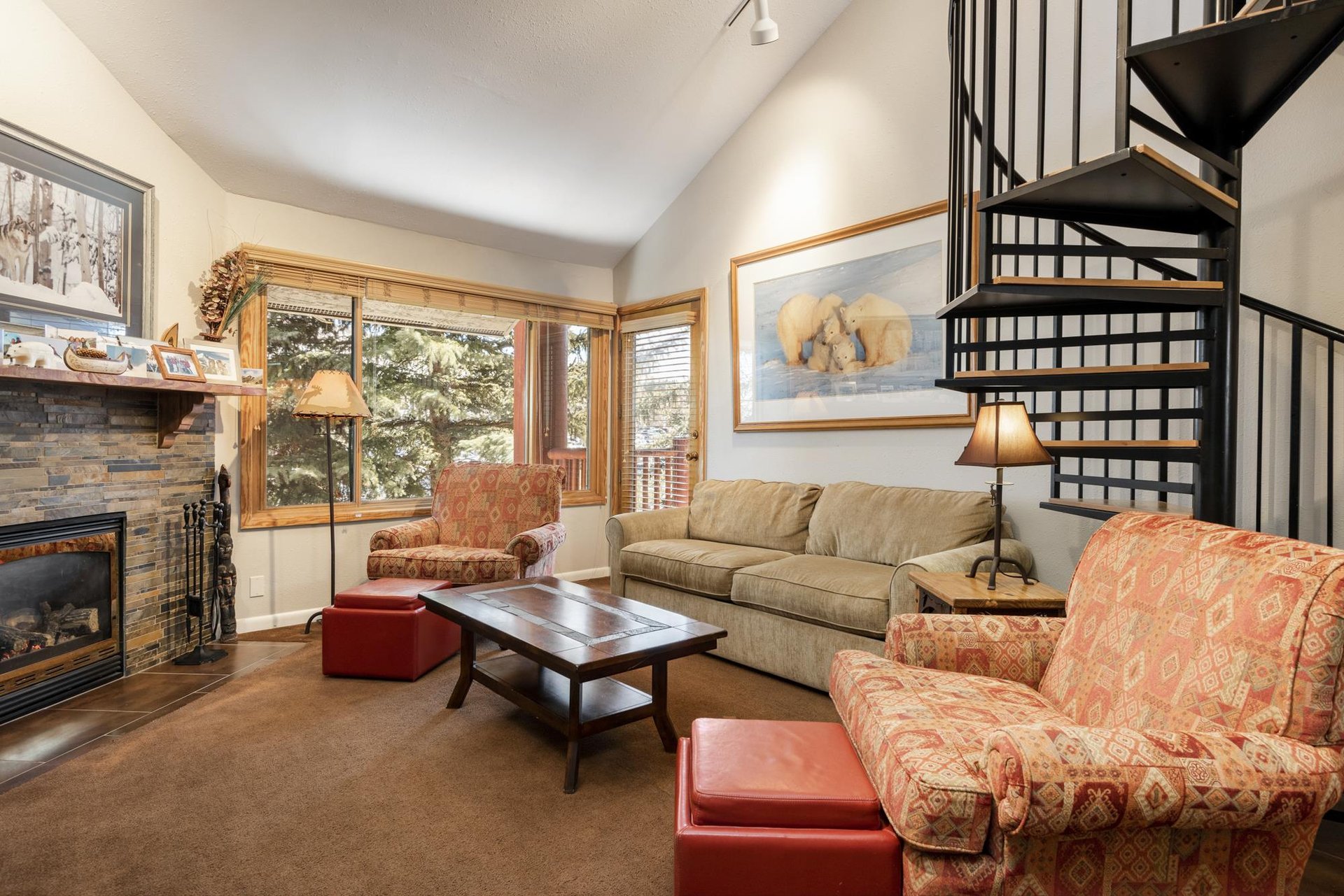 Spacious mountainstyle living room with comfortable seating, large windows and spiral staircase