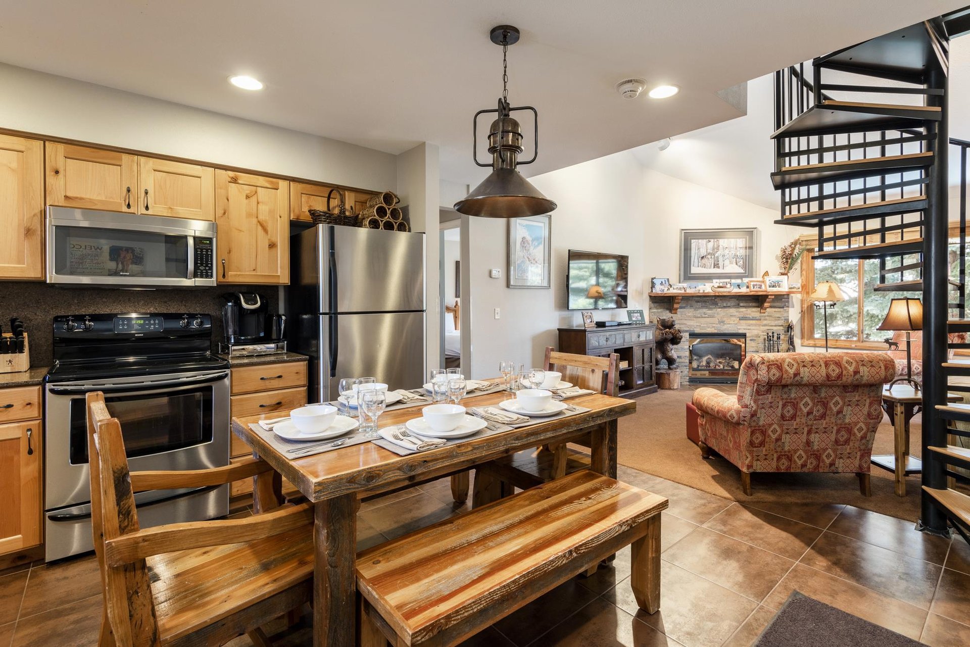 Open kitchen and dining area with wood cabinetry, stainless appliances and rustic dining table with seating for 6