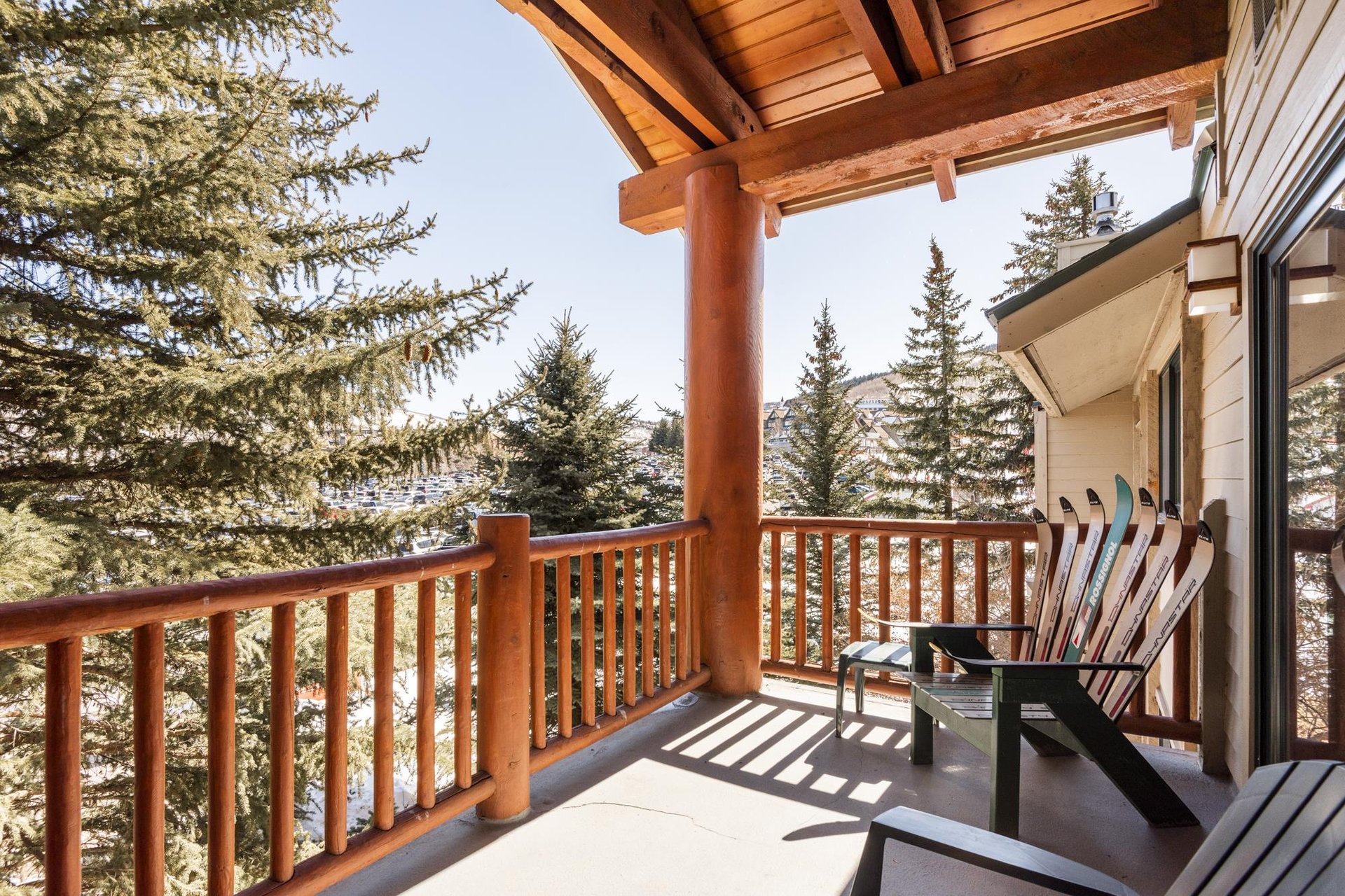 Private covered patio with rustic wood railing and peaceful views of the surrounding evergreen trees