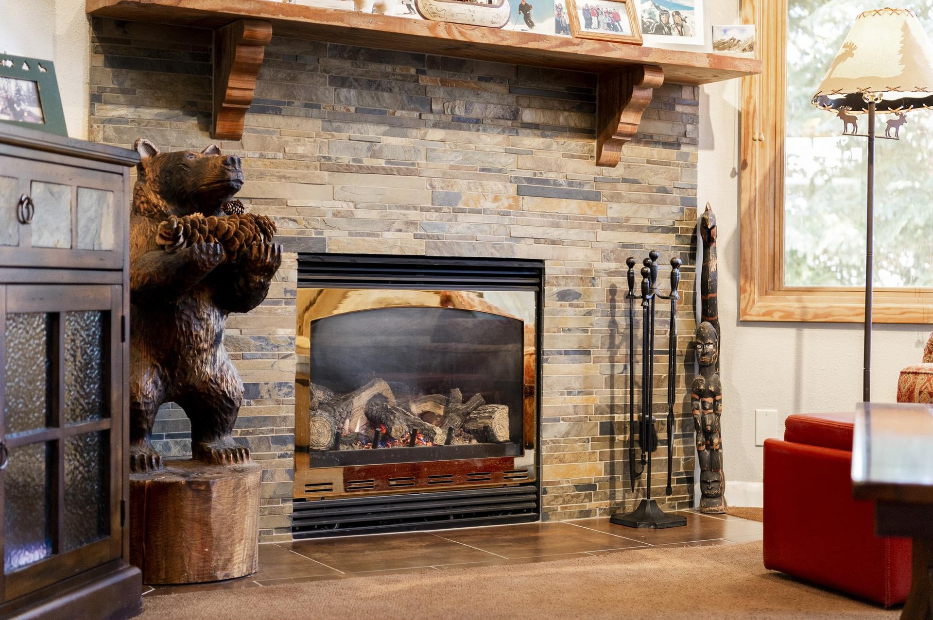 Cozy stone gas fireplace with rustic wood mantel and mountaininspired décor in the living room