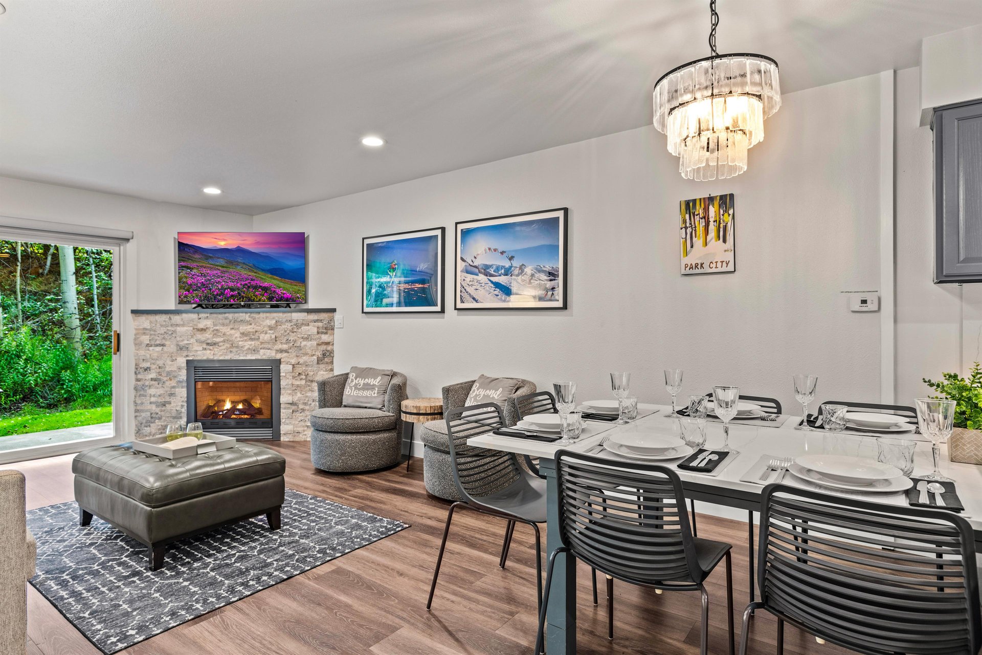Bright dining area with seating for 6 people leading into a comfortable living room with a stone gas fireplace and TV.