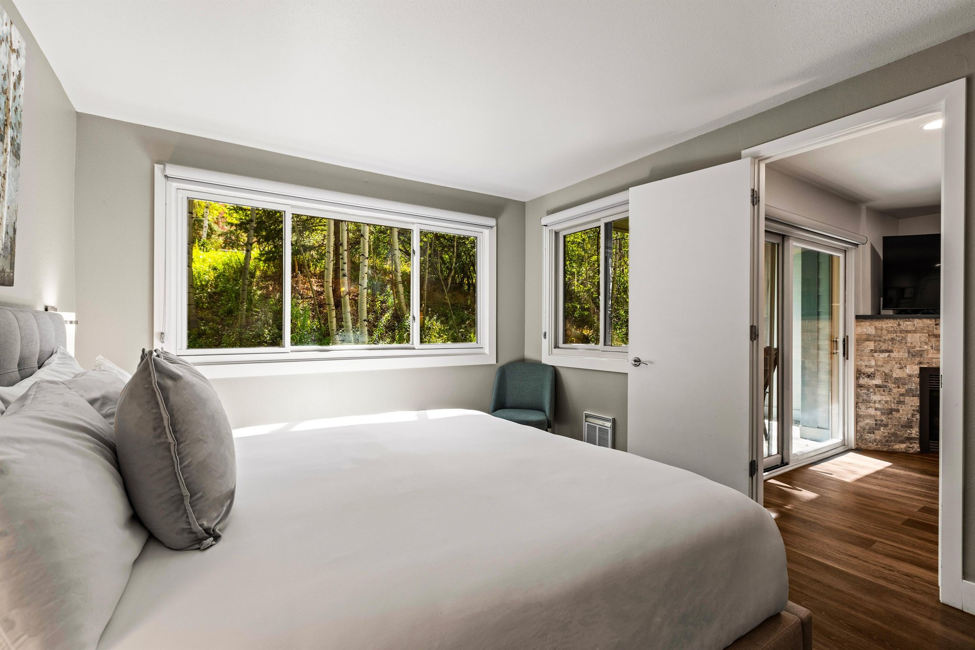 Bright king bedroom with large windows overlooking a peaceful grove of aspen trees