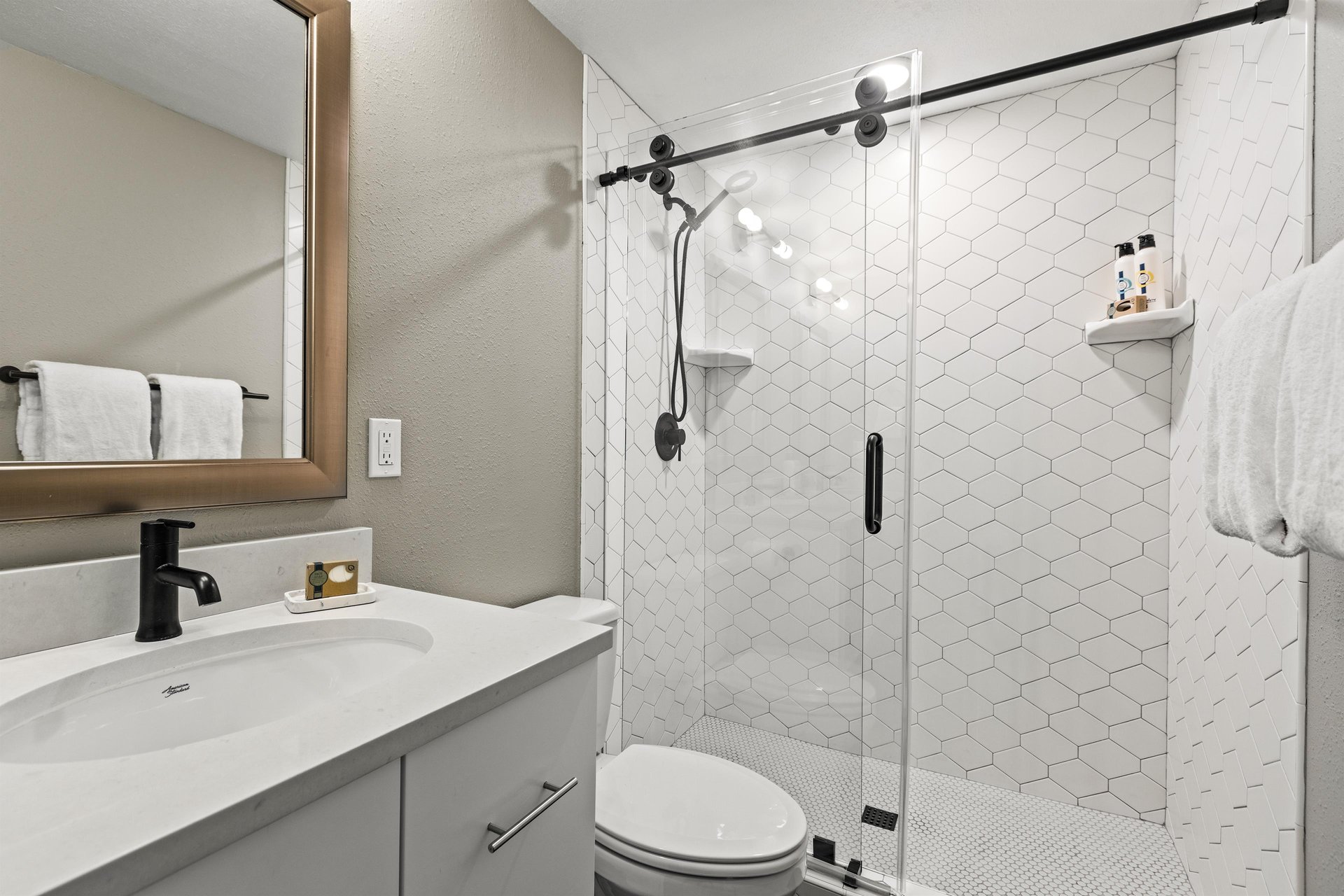 Master Bathroom featuring a glass walkin shower with white tile and modern black fixtures