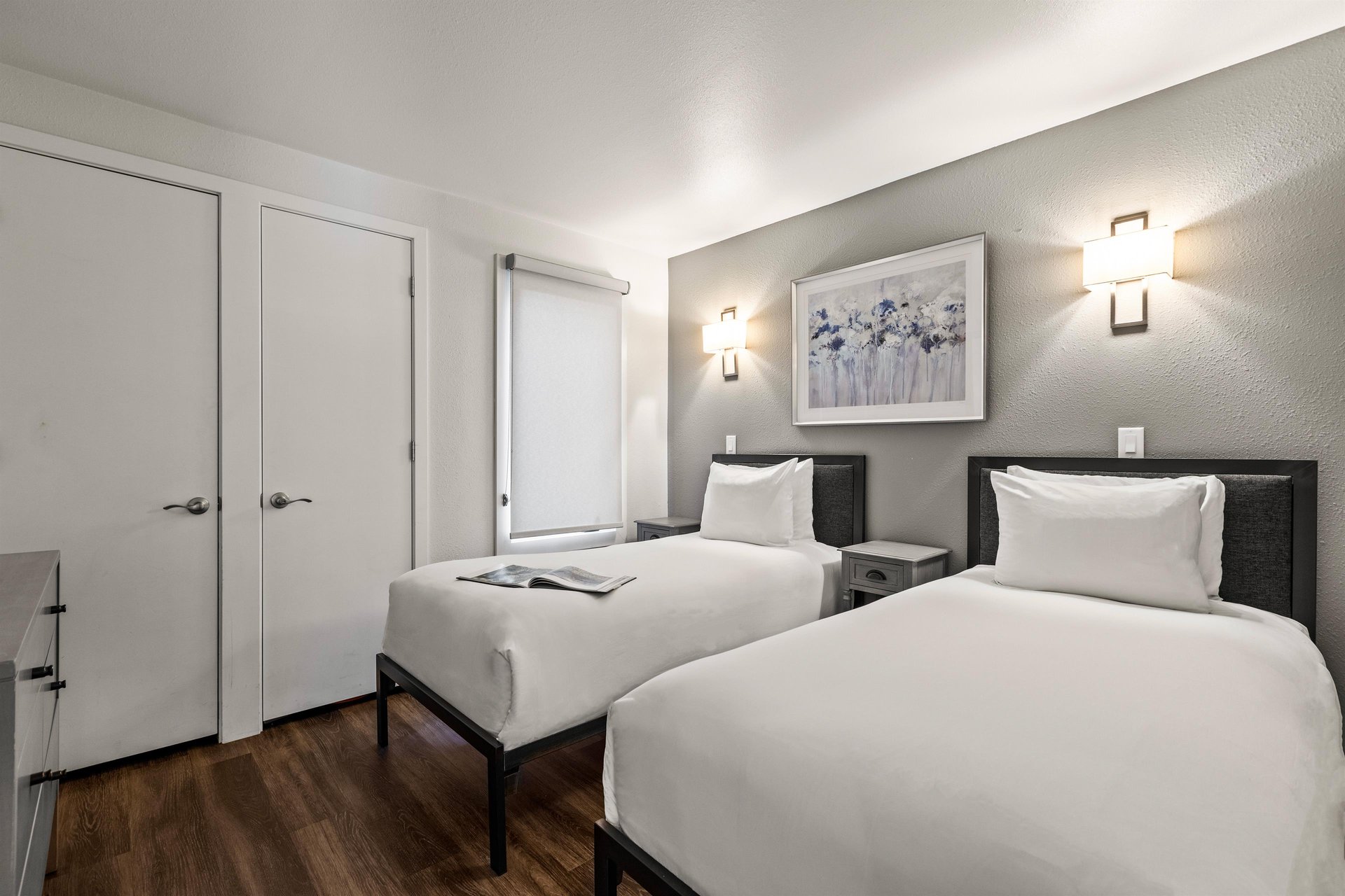 Guest bedroom with two twin beds, modern wall sconces, nightstands and contemporary mountaininspired artwork