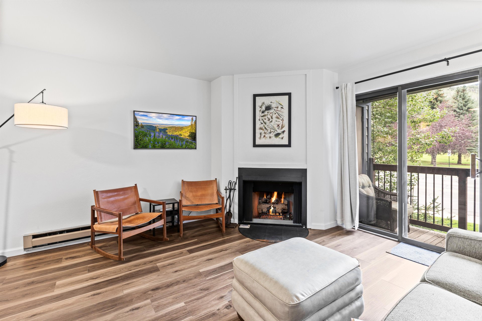 The living room offers a flat screen TV, wood burning fireplace, and nice sitting area with two chairs next to the fire.