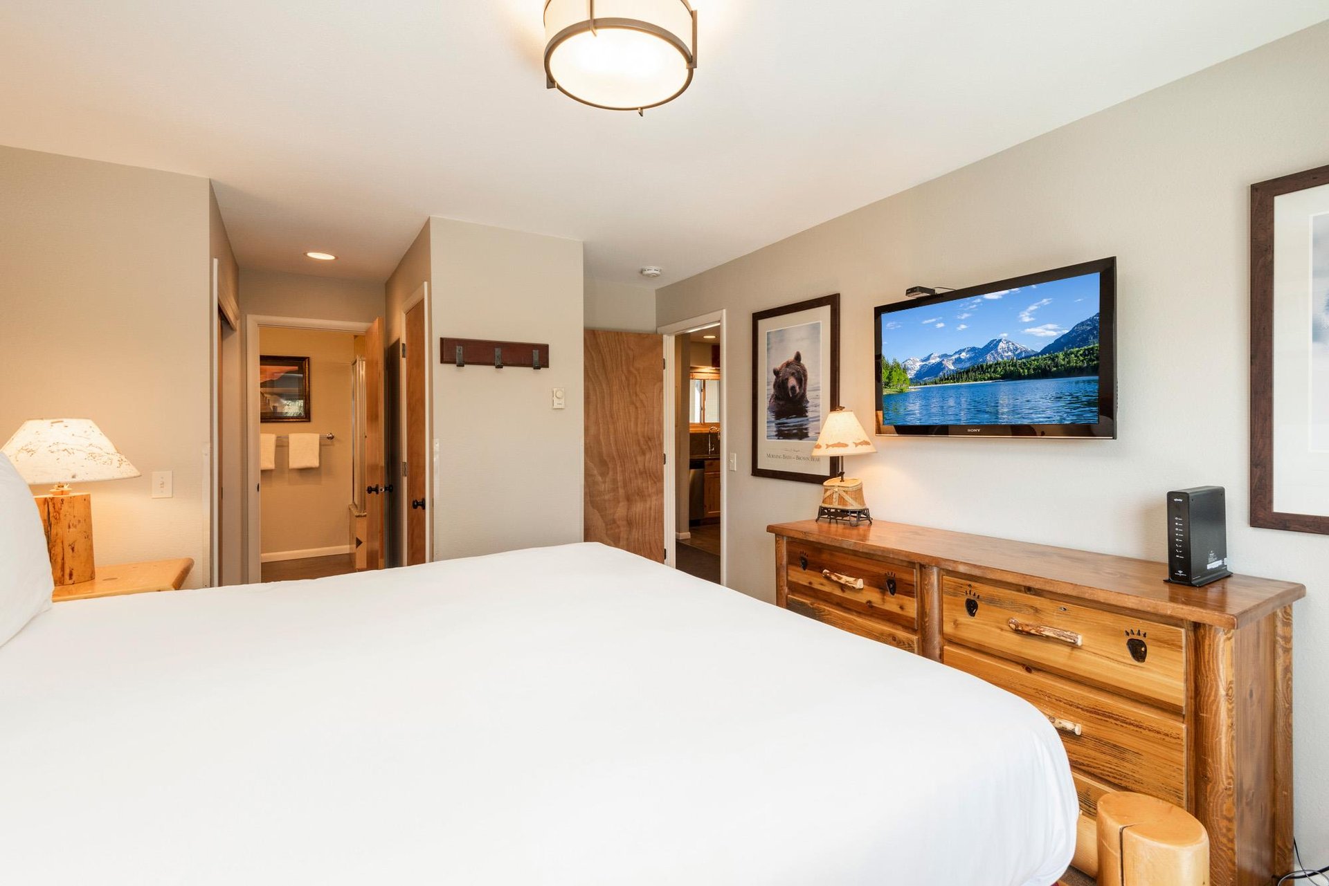 Cozy main bedroom with logframe bed, flatscreen TV, wood furnishings and warm mountaininspired décor