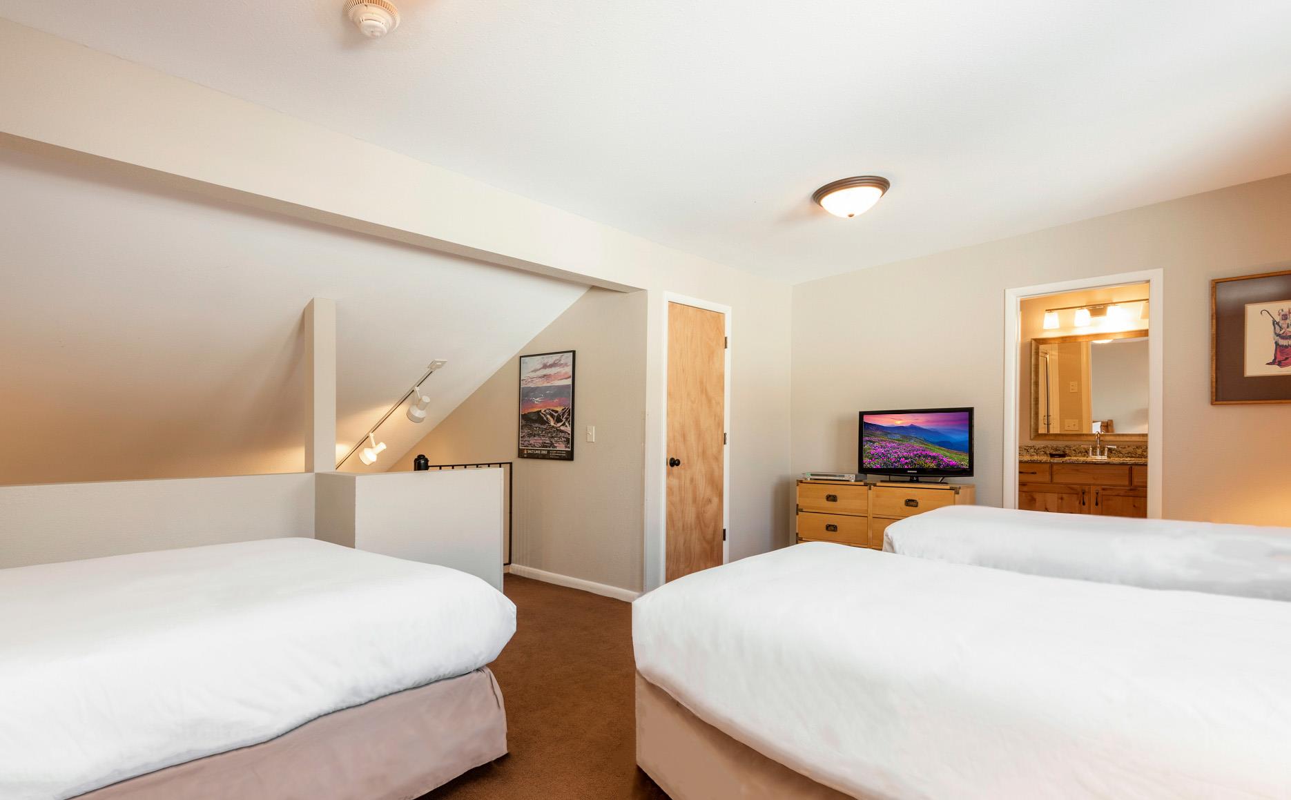 Spacious open loft with two twin beds, one queen bed, TV, dresser and convenient access to the stairs