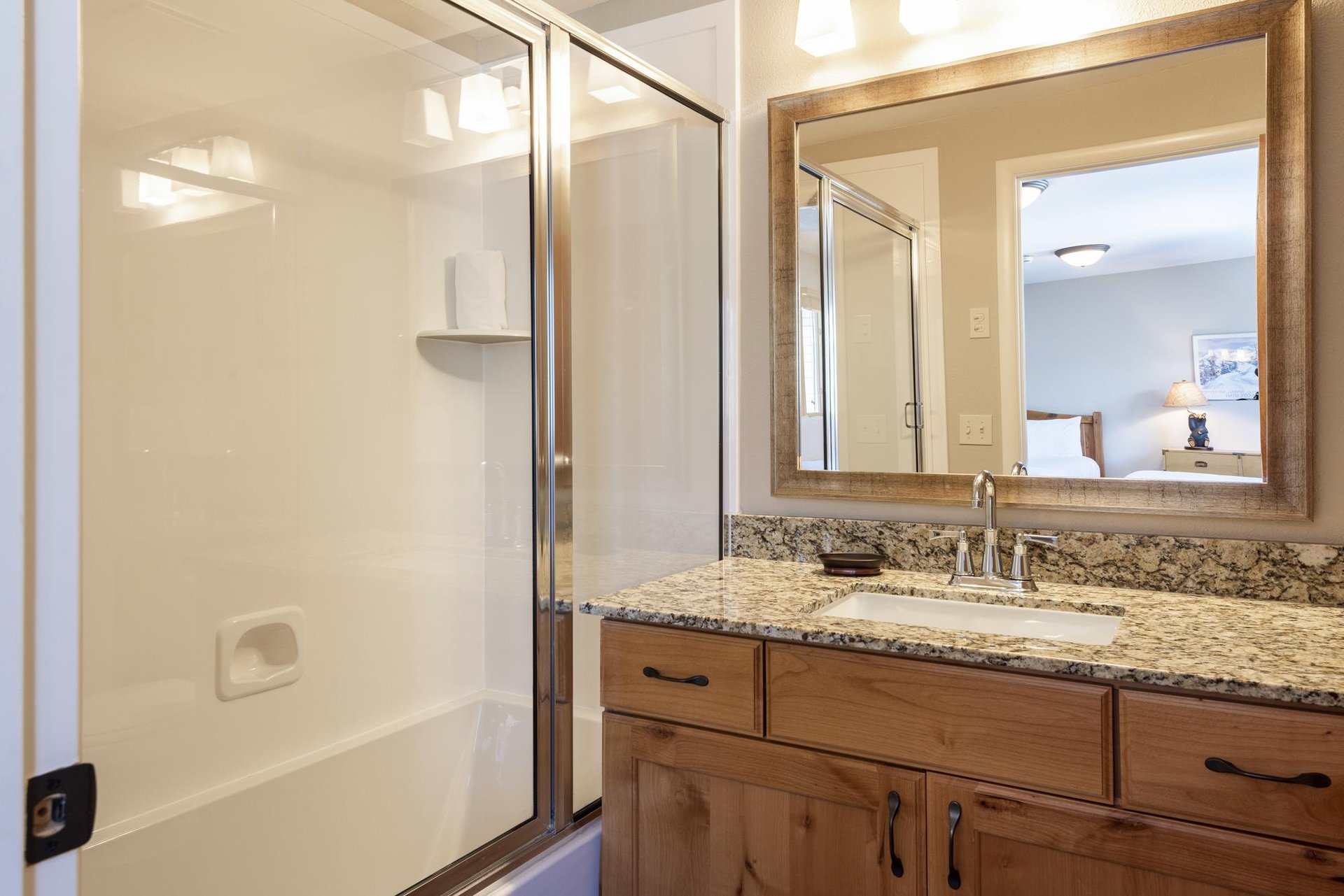 Third bathroom with granite vanity, wood cabinetry, large mirror and tub and shower combination