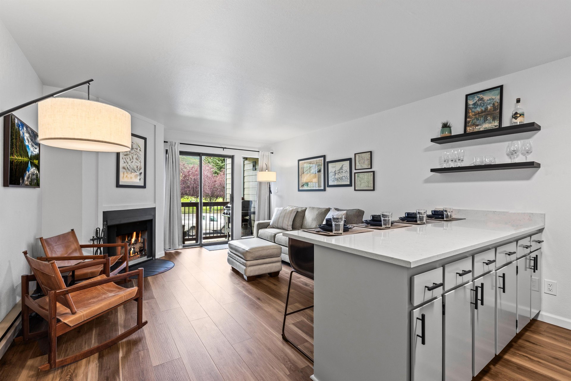 Snowcrest 207s living room has a cozy wood burning fireplace, a grey sofa and two leather chairs.