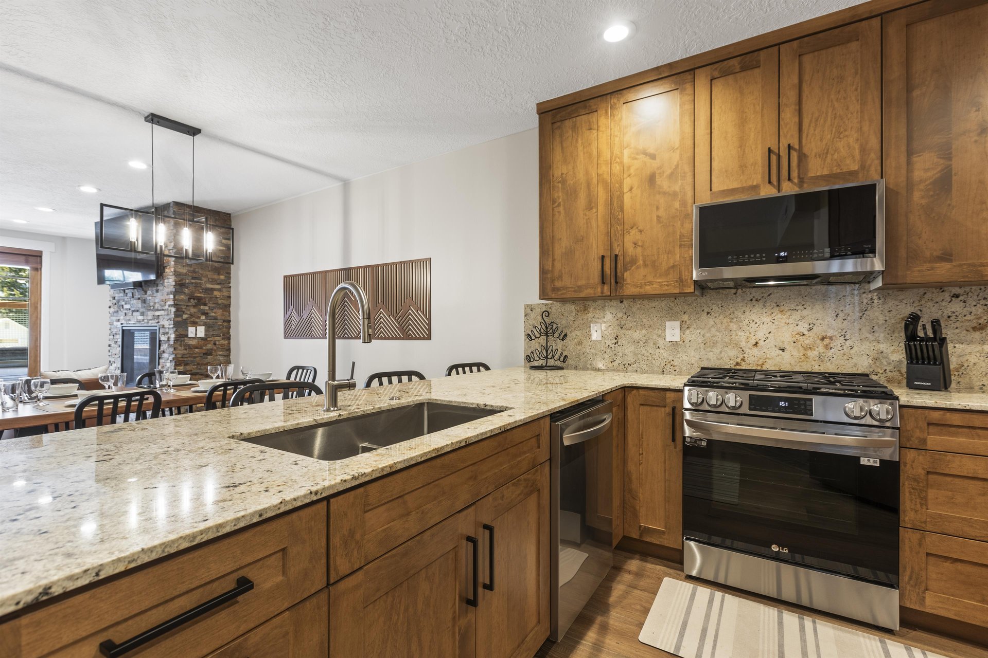 Full kitchen with granite countertops, wood cabinetry, stainless steel appliances and breakfast bar.