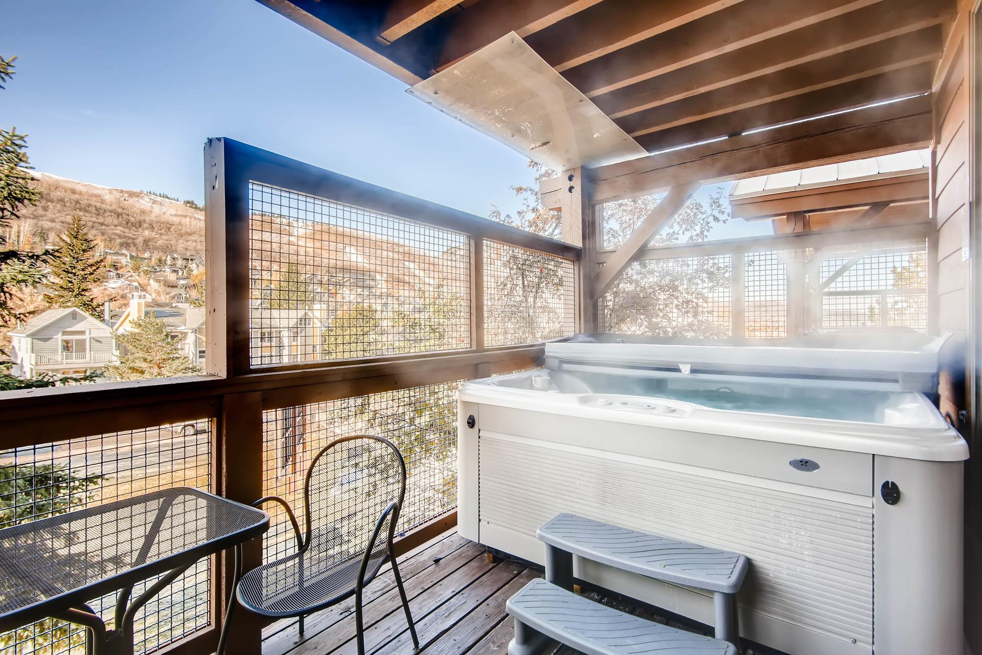 Private covered patio with hot tub, seating and mountain views.
