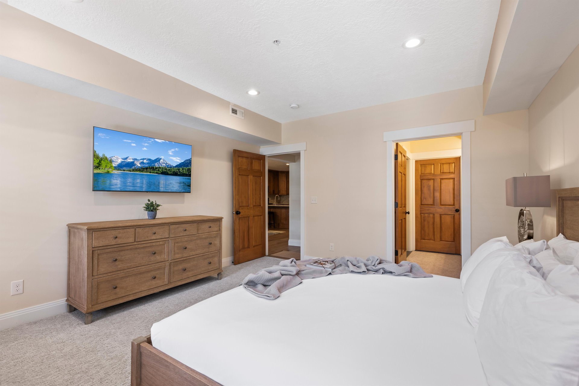 Spacious main bedroom with king bed, wallmounted TV, wood dresser and direct access to the ensuite bathroom.