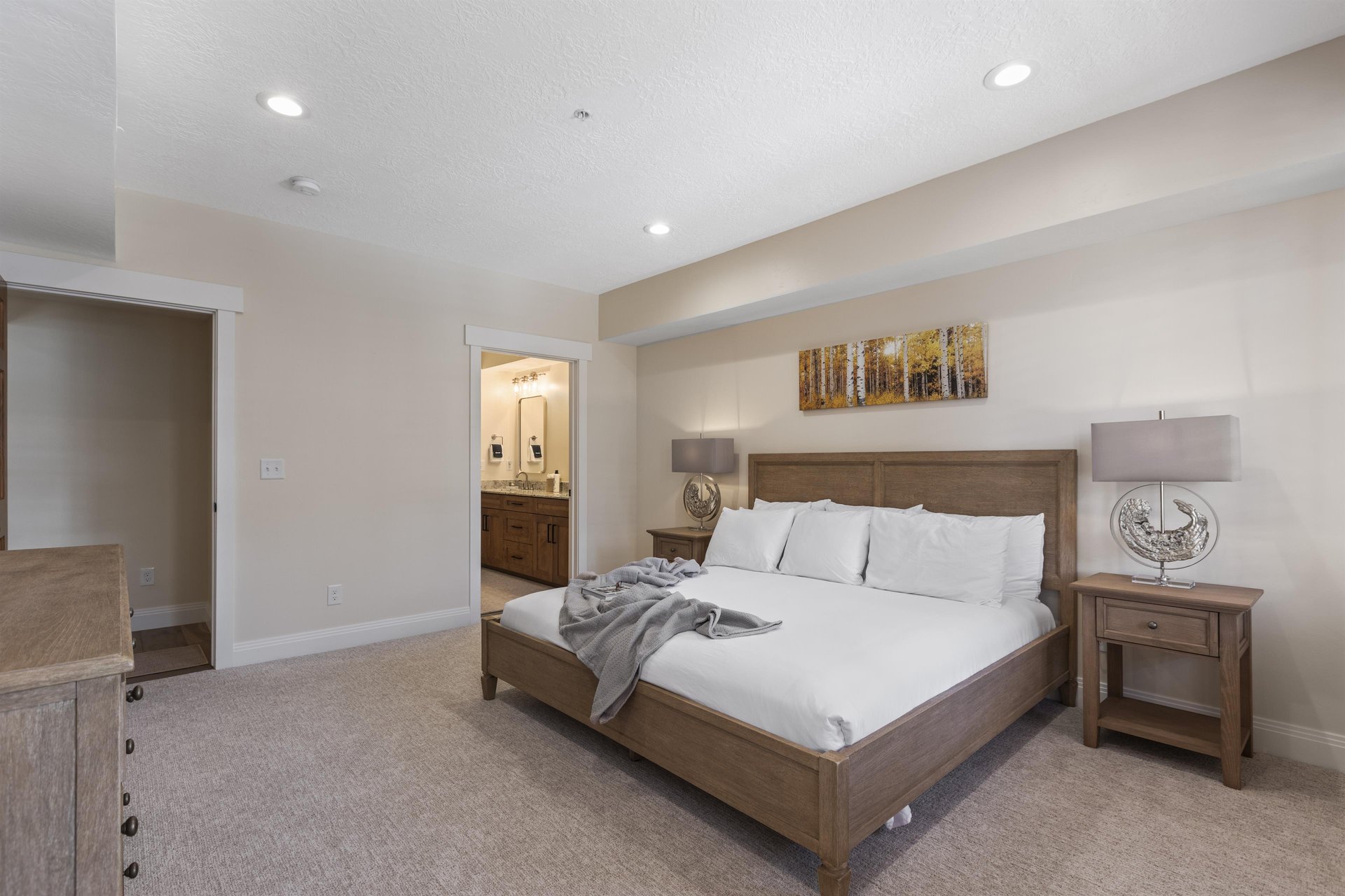 Main bedroom with king bed, bedside tables, recessed lighting and open access to the private ensuite bathroom.