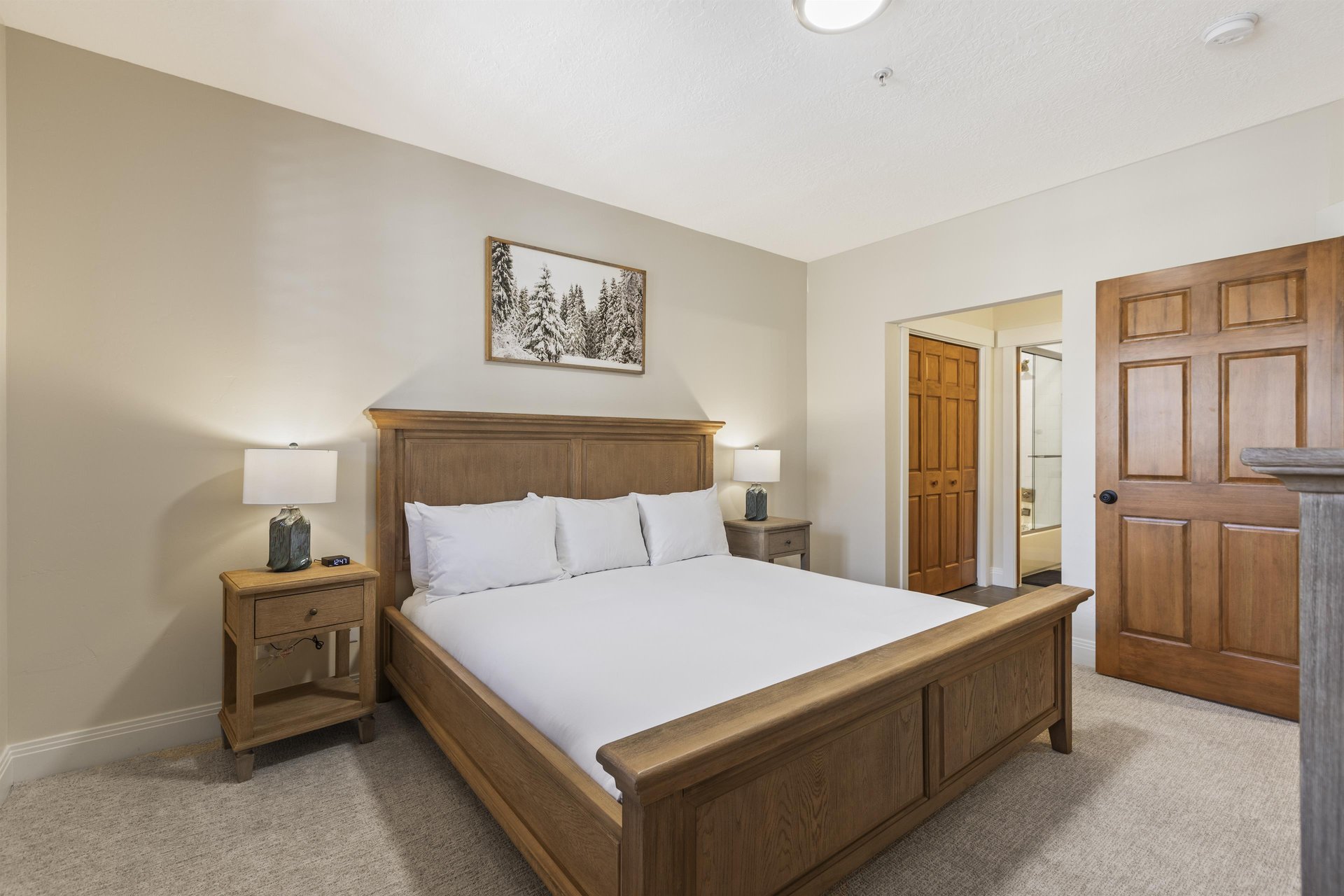 Second main bedroom with king bed, matching wood nightstands, bedside lamps and direct access to the ensuite bathroom.