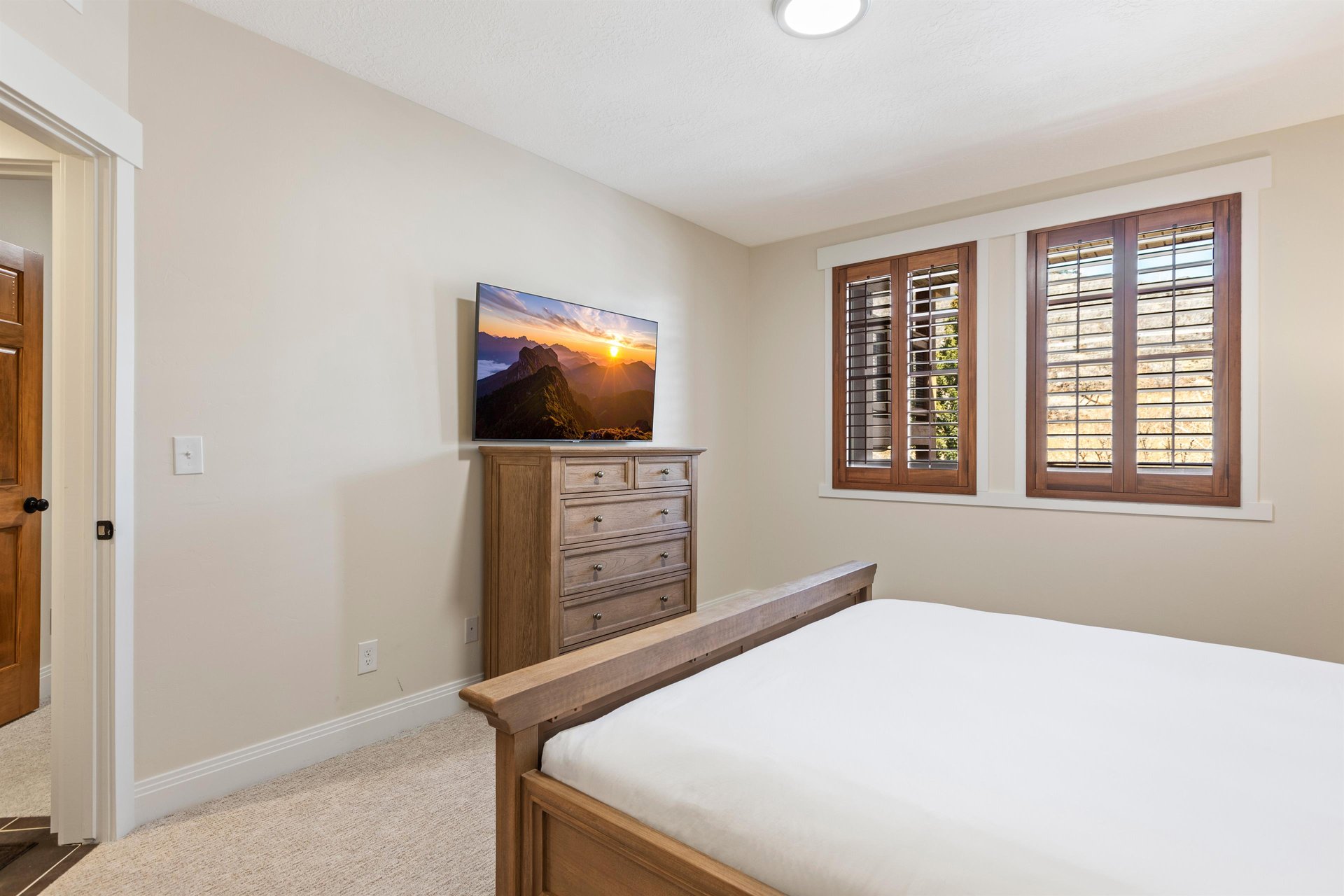 Second main bedroom with king bed, wood dresser, TV and windows with wood shutters for added privacy.