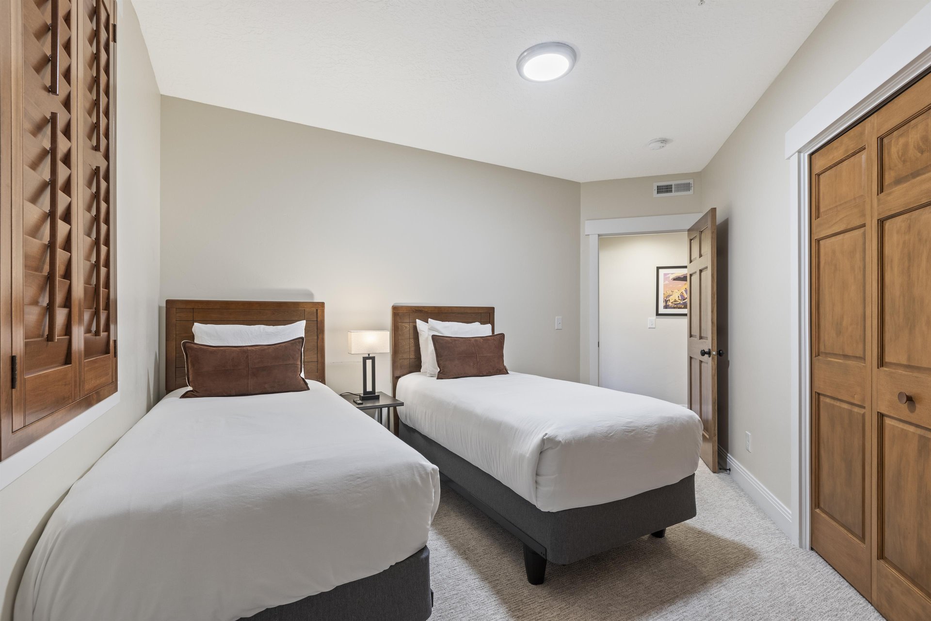 Third bedroom with two twin beds, matching wood headboards and bedside table, with beds convertible to a king.