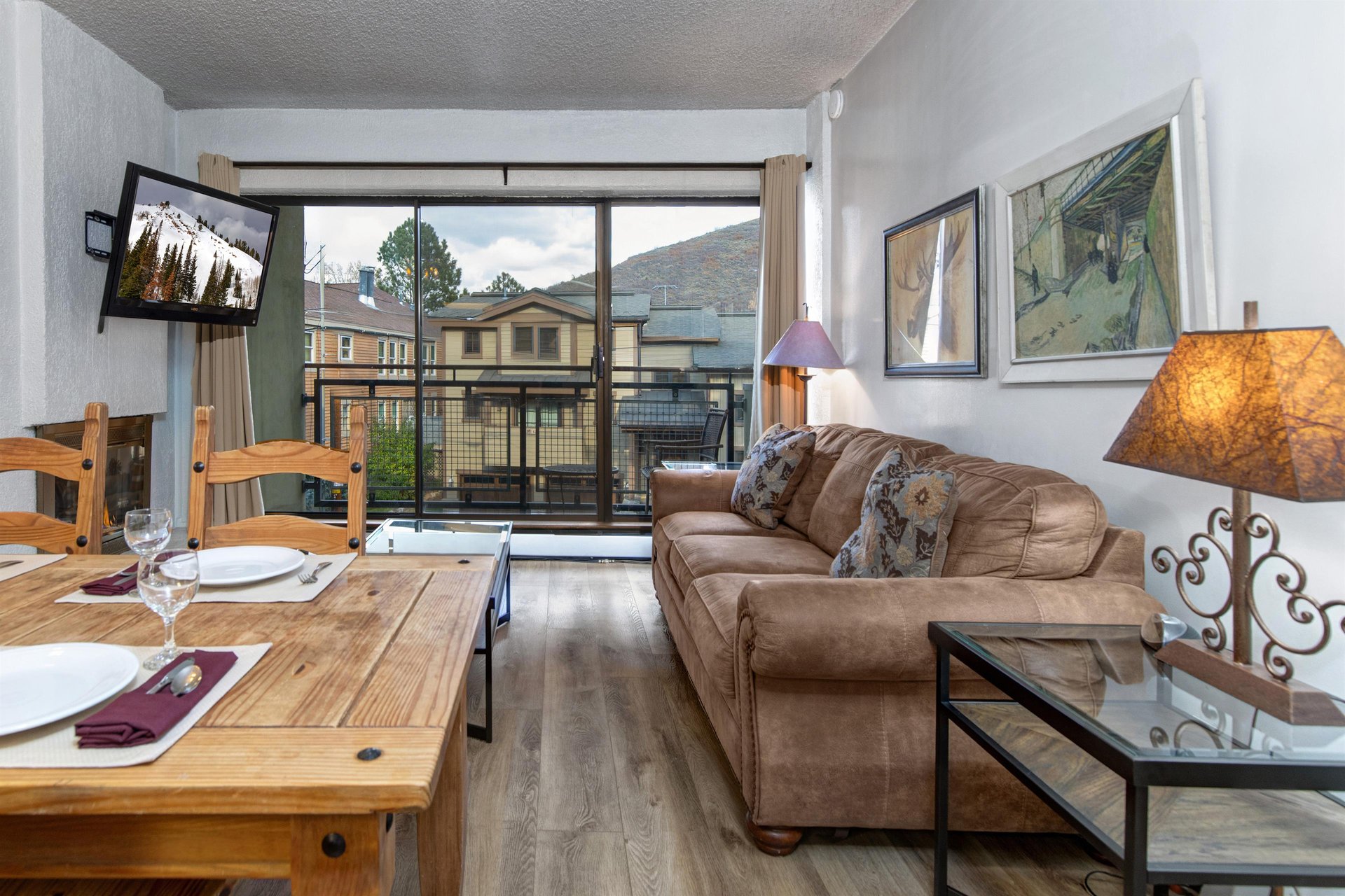 Bright living room with leather sofa, wood coffee table and floortoceiling windows overlooking the mountains.