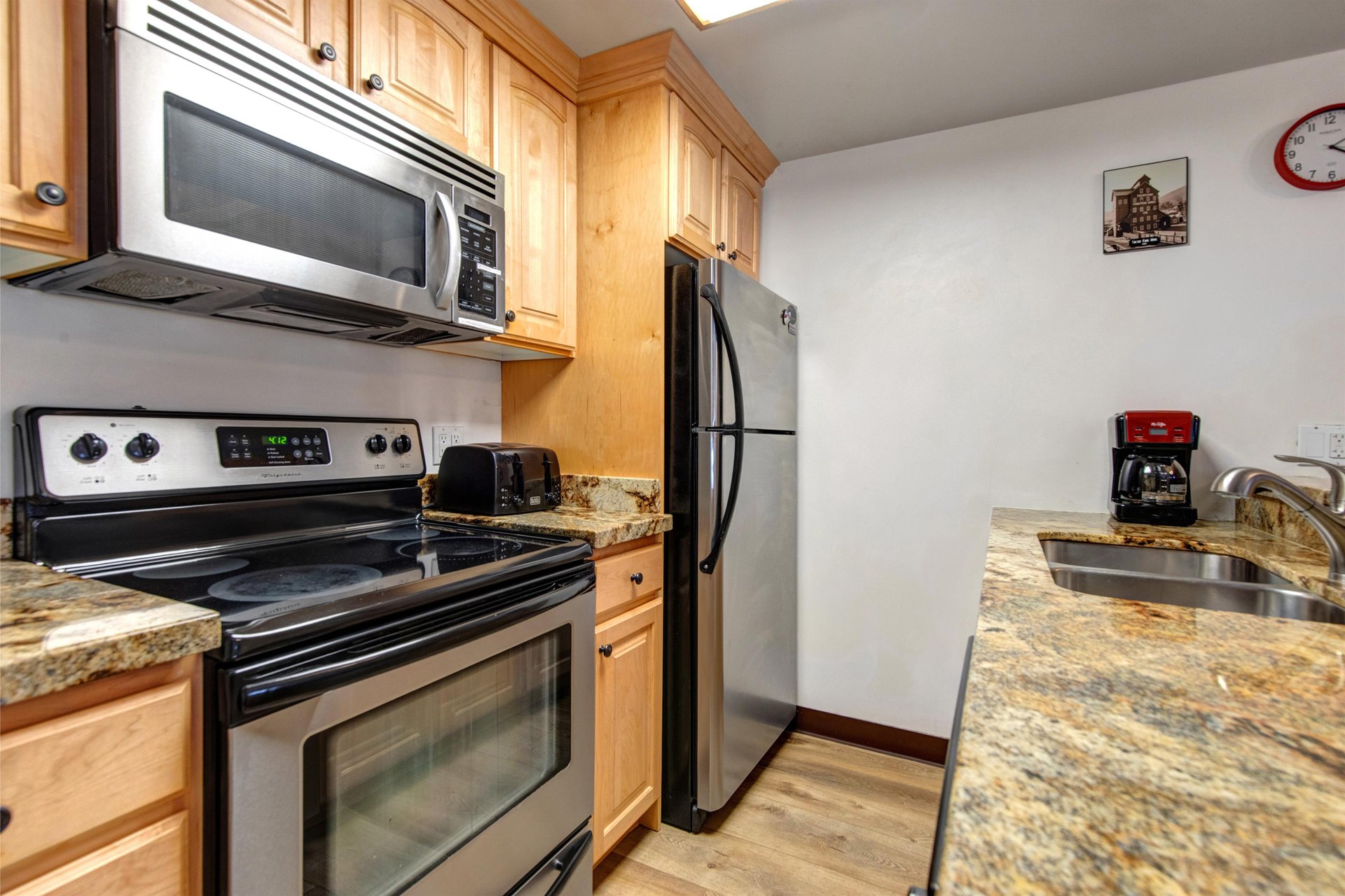 Full kitchen with wood cabinetry and black and stainless steel appliances.