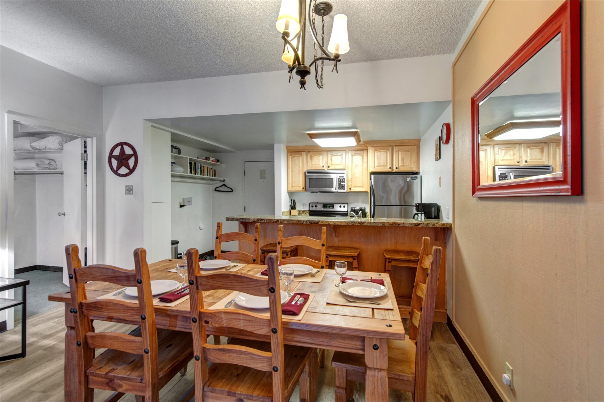 Dining area with wood table, seating for six and an open view into the kitchen and breakfast bar.