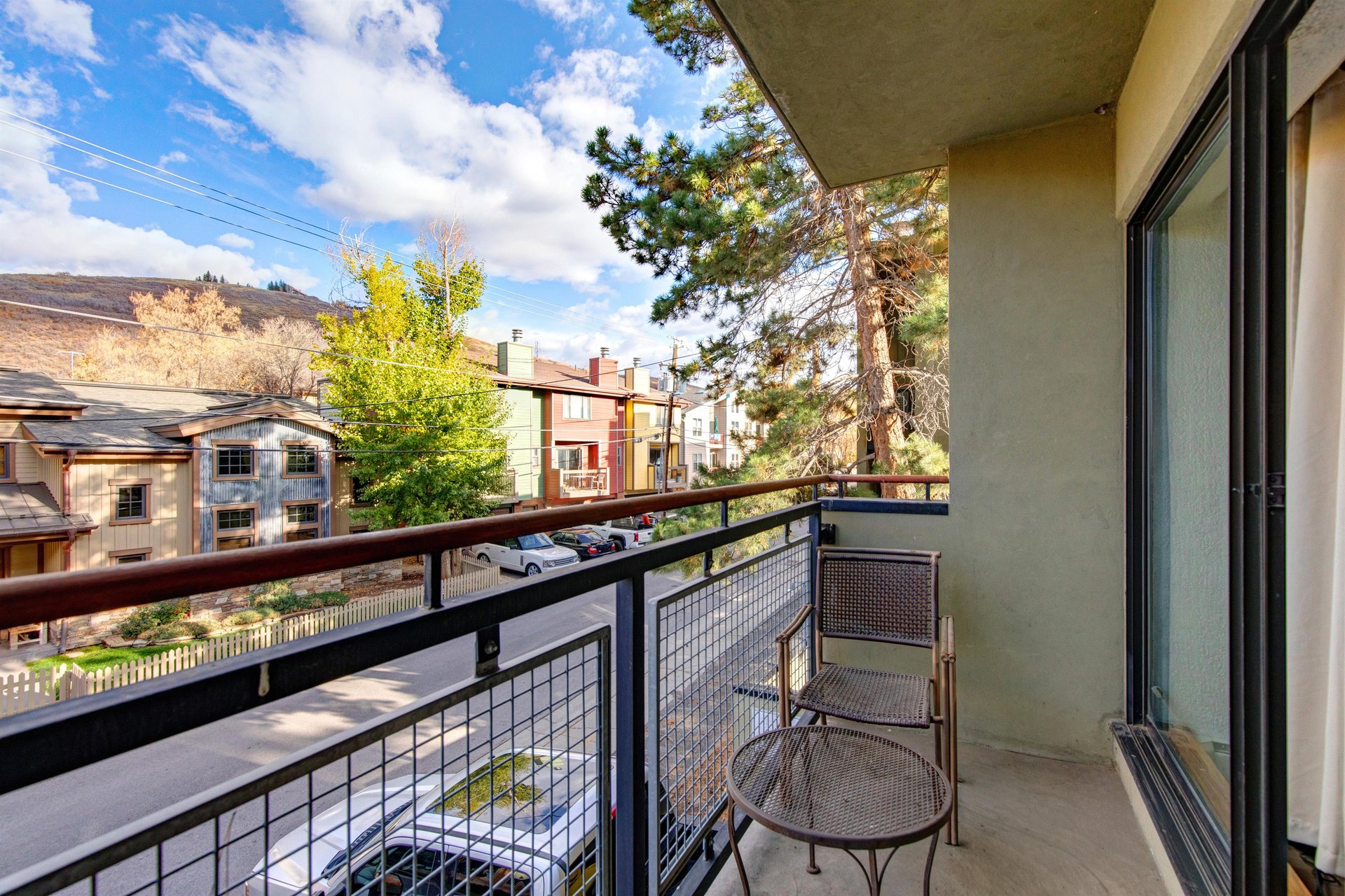 Private balcony overlooking the surrounding neighborhood with scenic mountain views in the distance with seating.